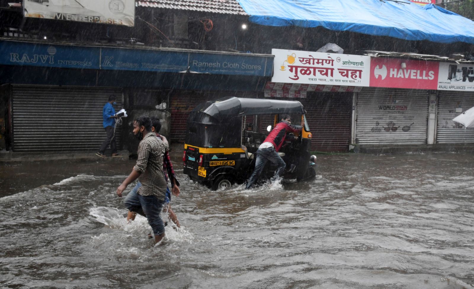epa09207304 Indian people wade through flooded street during heavy rainfall after cyclone Tauktae hits Mumbai and nearby areas, India, 17 May 2021. According to the India Meteorological Department (IMD) forecast, Cyclone Tauktae will make a landfall over the Gujarat coastal area, including Kerala, Karnataka, Maharashtra and Goa with a wind speed of around 150 kmph.  EPA/STR