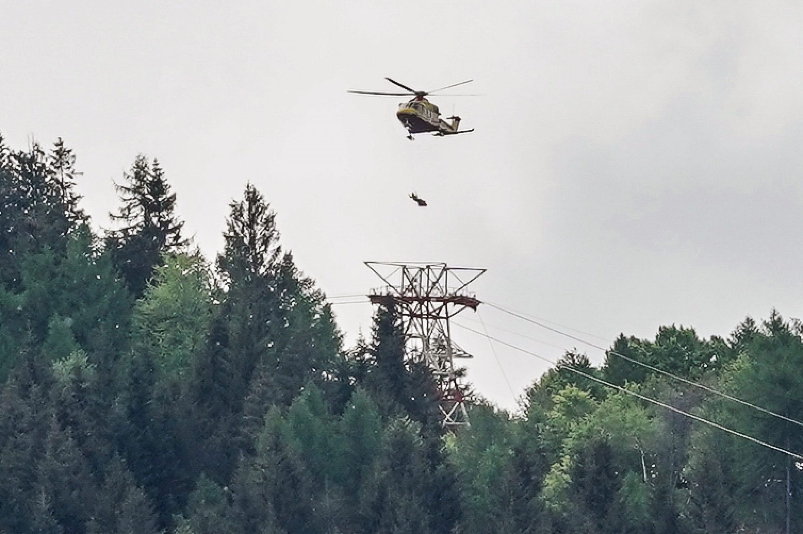 epa09222906 A helicopter flies over the area of the cable car accident, near Lake Maggiore, northern Italy, 23 May 2021. The cable car that connects Stresa with Mottarone has crashed, claiming 12 lives, according to the latest toll. Two children were seriously injured. The accident has been caused by the failure of a rope, in the highest part of the route which, starting from Lake Maggiore reaches an altitude of 1,491 meters.  EPA/TINO ROMANO