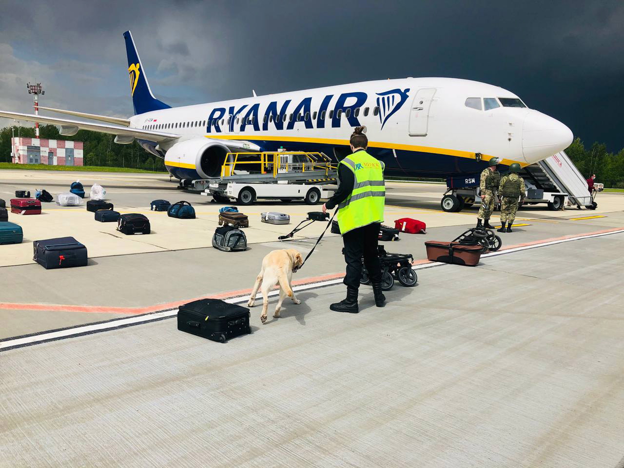 epa09224989 A handout photo made available by ONLINER.BY shows security with a sniffer dog checking the luggage of passengers in front of Ryanair Boeing 737-8AS (flight FR4978), carrying opposition figure Roman Protasevich, in Minsk, Belarus, 23 May 2021 (issued 24 May 2021). A Ryanair flight from Athens, Greece to Vilnius, Lithuania, with Belarus' opposition journalist Roman Protasevich onboard, was diverted and forced to land in Minsk on 23 May 2021, after an alleged bomb threat. Protasevich was detained by Belarusian Police after landing, as Belarusian Human Rights Center 'Viasna' reports, Lithuanian President Gitanas Nauseda demanded the immediate release of Protasevich.  EPA/ONLINER.BY HANDOUT -- BEST QUALITY AVAILABLE -- HANDOUT EDITORIAL USE ONLY/NO SALES