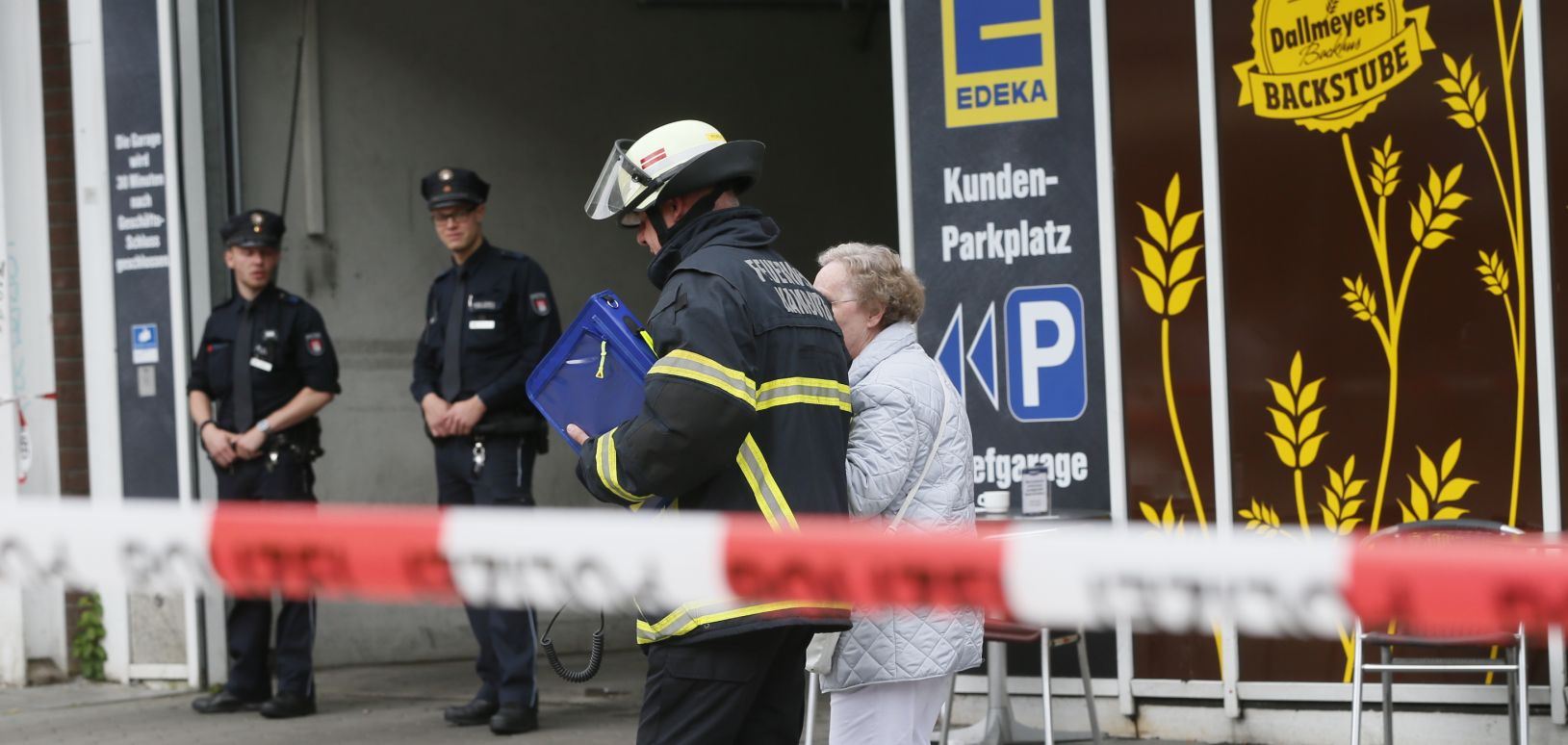 An elderly woman is accompanied by a firefighter after a knife attack at a supermarket in Hamburg, Germany, 28 July 2017. A man killed another person and injured several during a supermarket robbery in the district of Barmbek in Hamburg on 28 July. The suspect was arrested, the police informed on Twitter. Photo: Paul Weidenbaum/dpa