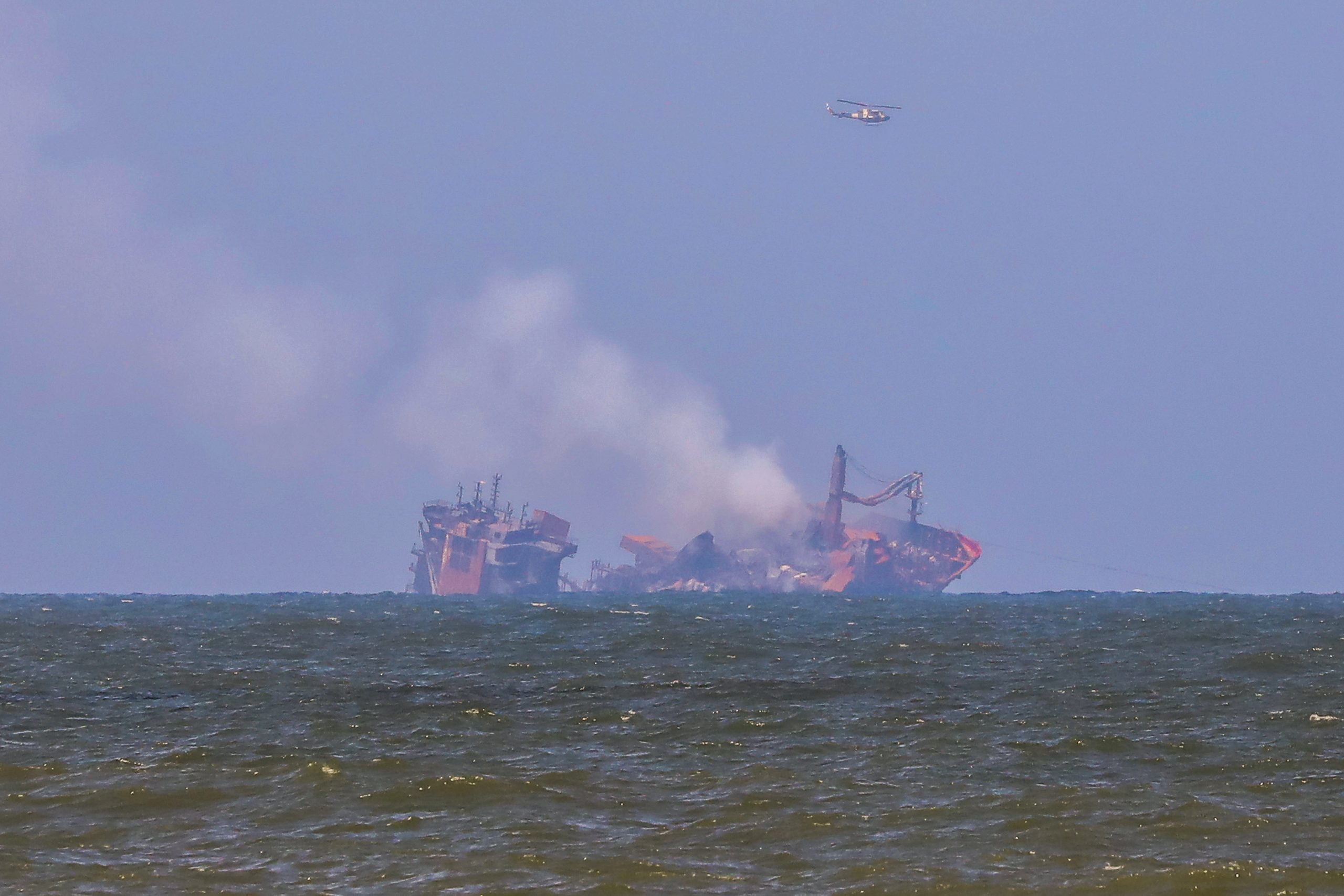 epa09242444 Smoke rises from the fire gutted and crippled container cargo vessel MV X-Press Pearl in Sri Lanka, 02 June 2021. The fire on the Singaporean flagged container cargo vessel MV X-Press Pearl, which had been burning for over 13 days, was doused and the salvage company began towing it towards deeper seas off the coast of Colombo on 02 June. However, latest reports by the Sri Lanka Navy stated that the towing operation had been halted as the stern of the ship was striking the seabed. They also reported that so far no oil spills have been observed. A huge amount of plastic granules and debris has already washed ashore on beaches from Colombo to Negombo and authorities now fear another wave of massive pollution should the 278 tonnes of bunker oil and 50 tonnes of gas in the Singapore-registered ship's fuel tanks leak into the Indian Ocean.  EPA/CHAMILA KARUNARATHNE