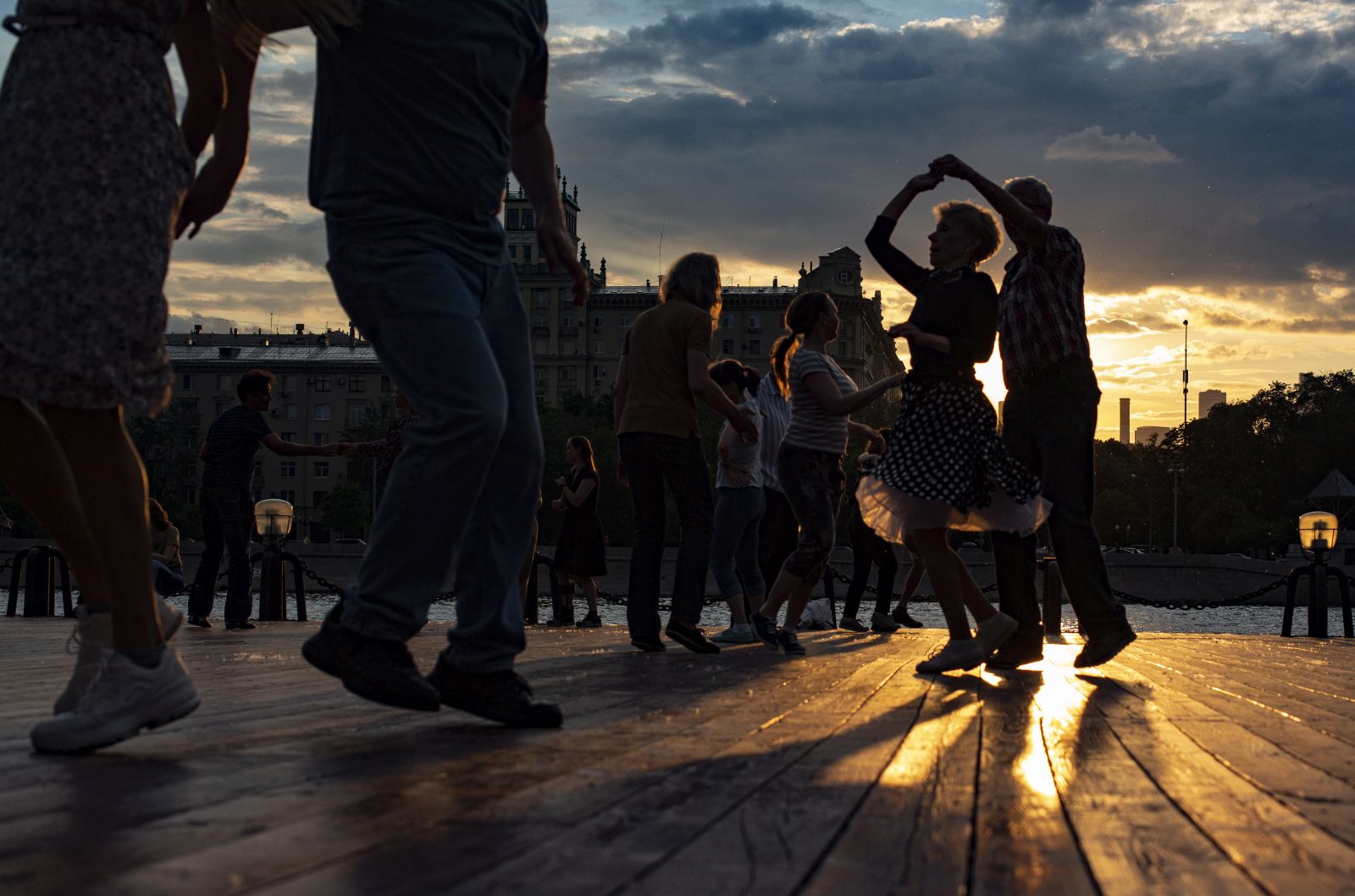epa09252284 People dance on the embankment of Moscow river during Sunset in downtown of Moscow, Russia, 06 June 2021. Several hundred people self-organize through social networks and come together on warm and fine evenings to dance bachata, kizomba, salsa and merengue.  EPA/SERGEI ILNITSKY