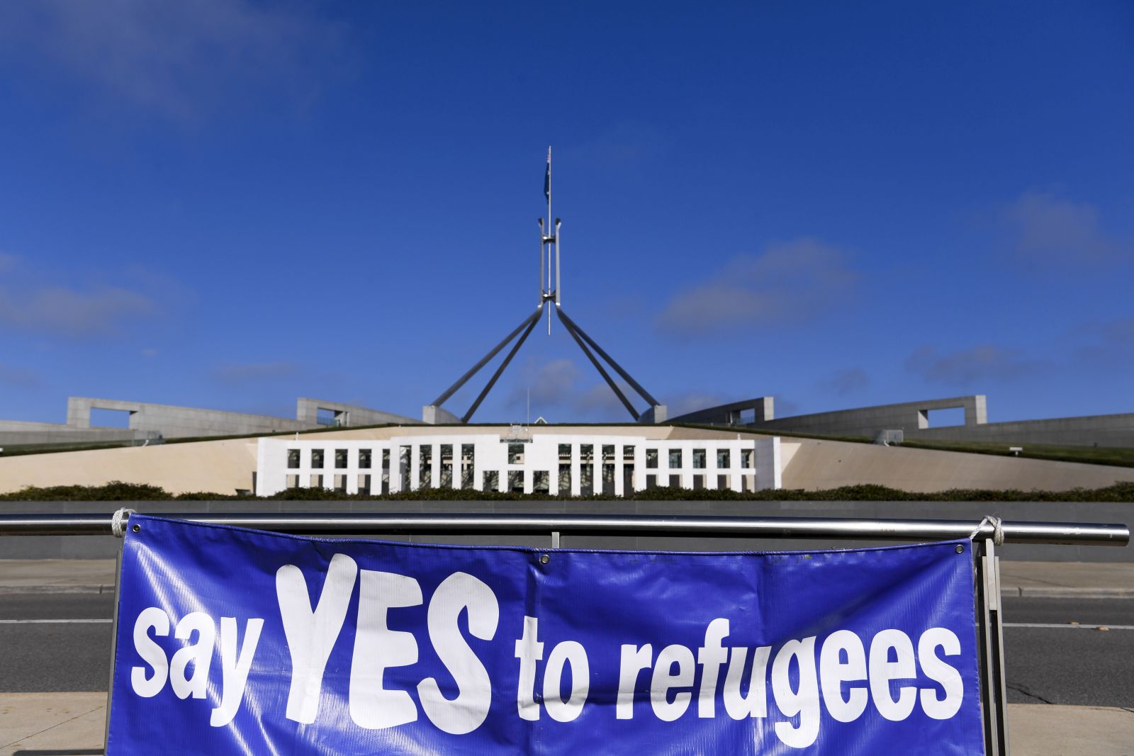 epa09272214 A sign reading 'say Yes to refugees' at a rally asking for a permanent resettlement plan for people seeking asylum and refugees outside Parliament House in Canberra, Australian Capital Territory, Australia, 15 June 2021.  EPA/LUKAS COCH AUSTRALIA AND NEW ZEALAND OUT