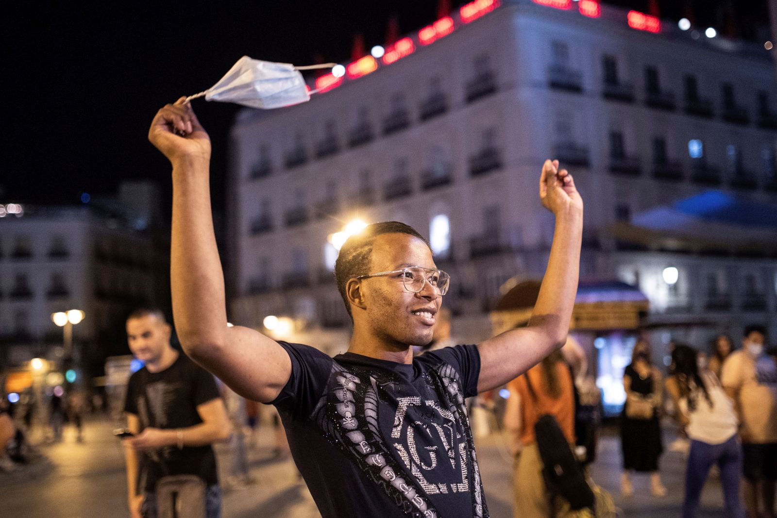 epa09302178 A young man celebrates the end of the mandatory use of facial masks outdoors in Puerta del Sol square in Madrid, Spain, early 26 June 2021. People are allowed to go without facial masks outdoors as long as social distancing is possible.  EPA/RODRIGO JIMENEZ