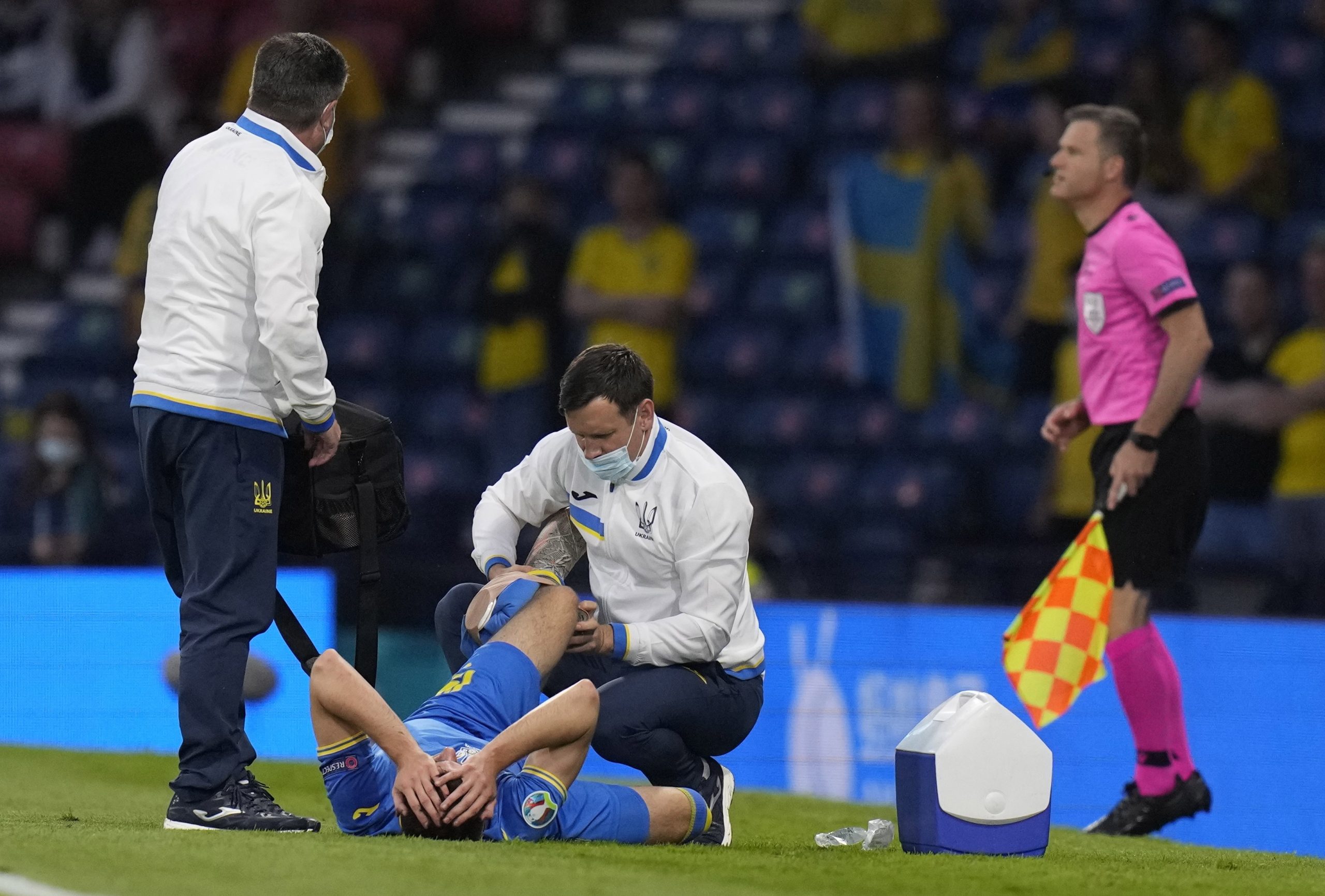 epa09312271 Artem Besyedin (bottom) of Ukraine receives medical assistance during the UEFA EURO 2020 round of 16 soccer match between Sweden and Ukraine in Glasgow, Britain, 29 June 2021.  EPA/Petr Josek / POOL (RESTRICTIONS: For editorial news reporting purposes only. Images must appear as still images and must not emulate match action video footage. Photographs published in online publications shall have an interval of at least 20 seconds between the posting.)