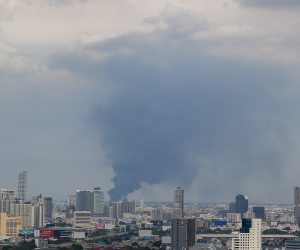 epa09323237 Black smoke billows among tall buildings following an explosion at a factory in Samui Prakan, Thailand, 05 July 2021. An explosion followed by a fire destroyed a factory producing plastic foam and plastic pellets in Bang Phli district of Samut Prakan, injuring at least 21 people according to officials. The explosion caused damage to surrounding buildings, and the Disaster Prevention and Mitigation Department has advised residents in a 5 kilometer radius to evacuate until further notice.  EPA/DIEGO AZUBEL