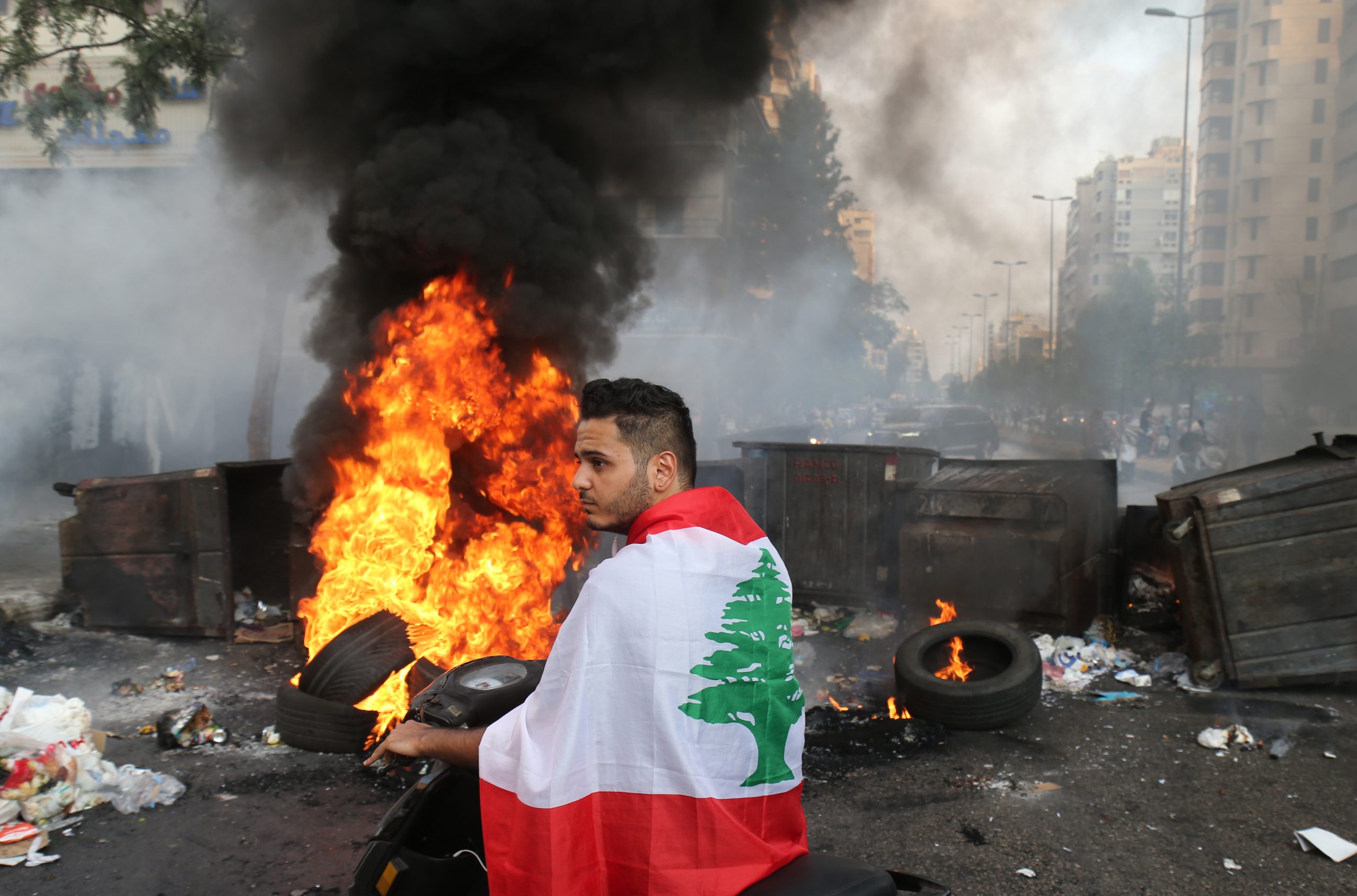 epaselect epa09347091 A Lebanese man drives as protesters block the roads with garbage bins and burning tires during protests after Lebanese Prime Minister-Designate Saad Hariri abandoned his effort to form a new government, in Beirut, Lebanon, 15 July 2021. Hariri, who was tasked nine months ago with forming the new government, said on 15 July he is stepping down a day after he presented the cabinet proposal to President Michel Aoun who has not accepted the government.  EPA/NABIL MOUNZER