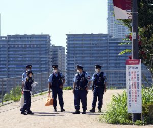epa09349795 Police officers gather at a closed access to the Olympic Village (seen in the background) in Tokyo, Japan, 17 July 2021. The Tokyo Olympics organisers confirmed the first COVID-19 case in the Tokyo athletes' village less than a week before the opening of the Games.  EPA/FRANCK ROBICHON