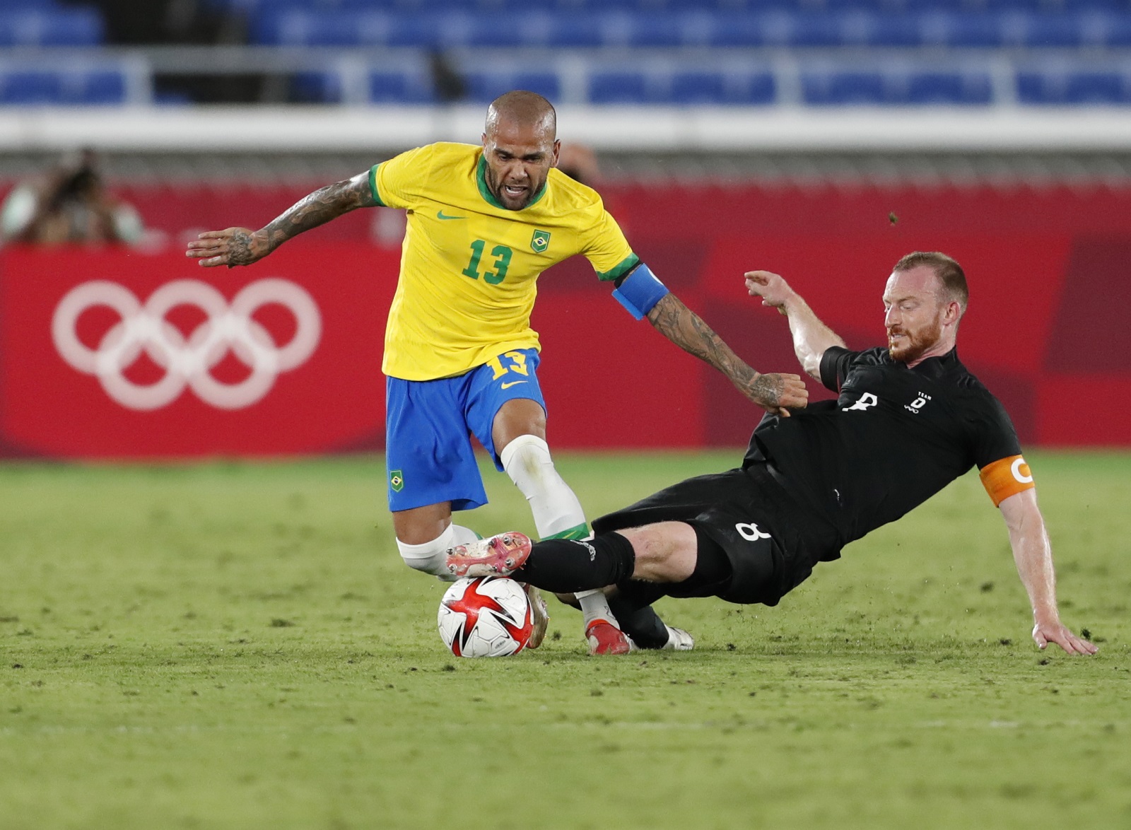 epa09358120 Dani Alves (L) of Brazil in action against Maximillian Arnold (R) of Germany during the men's soccer group stage match between Germany and Brazil at the Tokyo 2020 Olympic Games in Yokohama, Japan, 22 July 2021.  EPA/KIYOSHI OTA