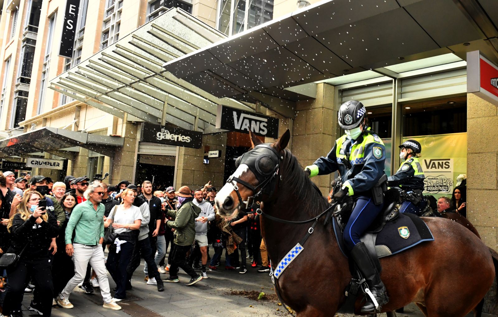 epaselect epa09360821 Protesters throw plastic bottles and pot plants at mounted police at Sydney Town Hall during the 'World Wide Rally For Freedom' anti-lockdown rally at Hyde Park in Sydney, New South Wales, Australia, 24 July 2021.  EPA/MICK TSIKAS AUSTRALIA AND NEW ZEALAND OUT