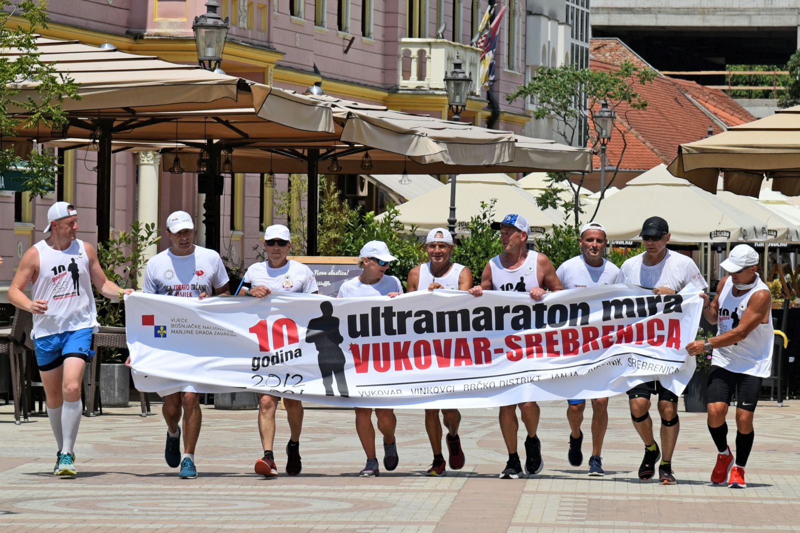 Vinkovci, 6.7.2021.- Iz spomen podruèja Ovèara u utorak je krenuo 10. jubilarni ultramaraton Vukovar-Srebrenica èiji æe sudionici od 6. do 10. srpnja istrèati 227 kilometara dug put od Ovèare do Potoèara (Srebrenica) u znak odavanja poèasti rtvama rata Vukovara i Srebrenice. Na slici maratonci po dolasku u Vinkovce prolaze pjeaèkom zonom u sreditu grada. 
foto HINA/ ua