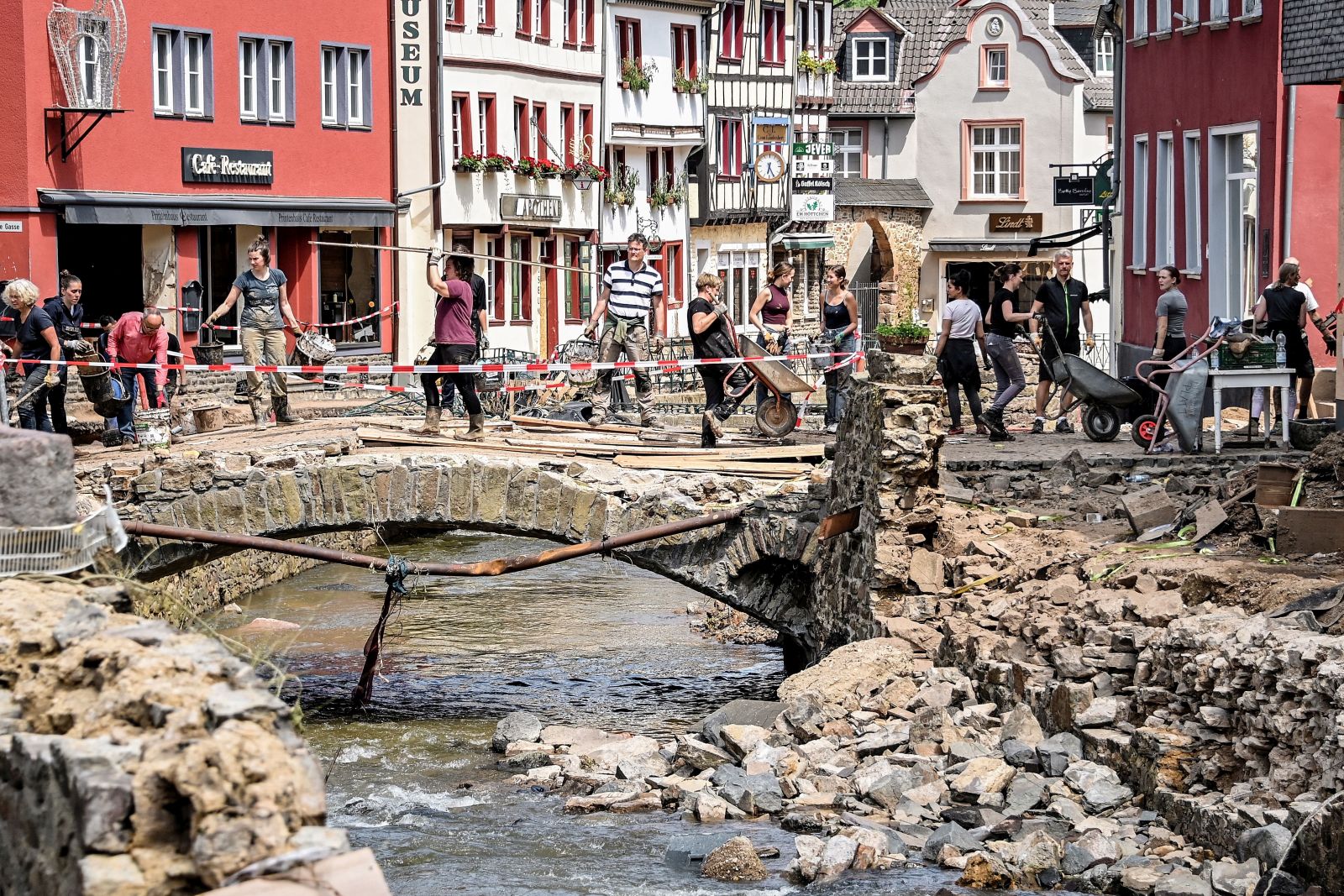 epa09356199 Residents clear debris out of the way after heavy flooding of the river Erft caused severe destruction in the village of Bad Muenstereifel, Euskirchen district, Germany, 20 July 2021 (issued 21 July 2021). Large parts of western Germany and central Europe were hit by flash floods in the night of 14 to 15 July, following days of continuous rain that destroyed buildings and swept away cars. The total number of victims in the flood disaster in western Germany rises to at least 170, with many hundreds still missing.  EPA/SASCHA STEINBACH