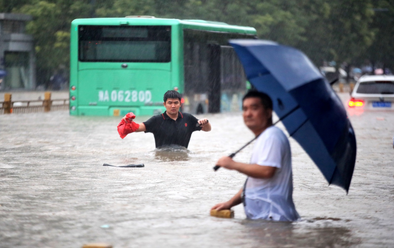 epa09356176 People walk in the flooded road after record downpours in Zhengzhou city in central China's Henan province Tuesday, July 20, 2021 (issued 21 July 2021). Heavy floods in Central China killed 12 in Zhengzhou city due to the rainfall yesterday, 20 July 2021, according to official Chinese media. Over 144,660 people have been affected by heavy rains in Henan Province since July 16, and over 10,000 had to be relocated, the provincial flood control and drought relief headquarters said Tuesday.  EPA/FEATURECHINA CHINA OUT
