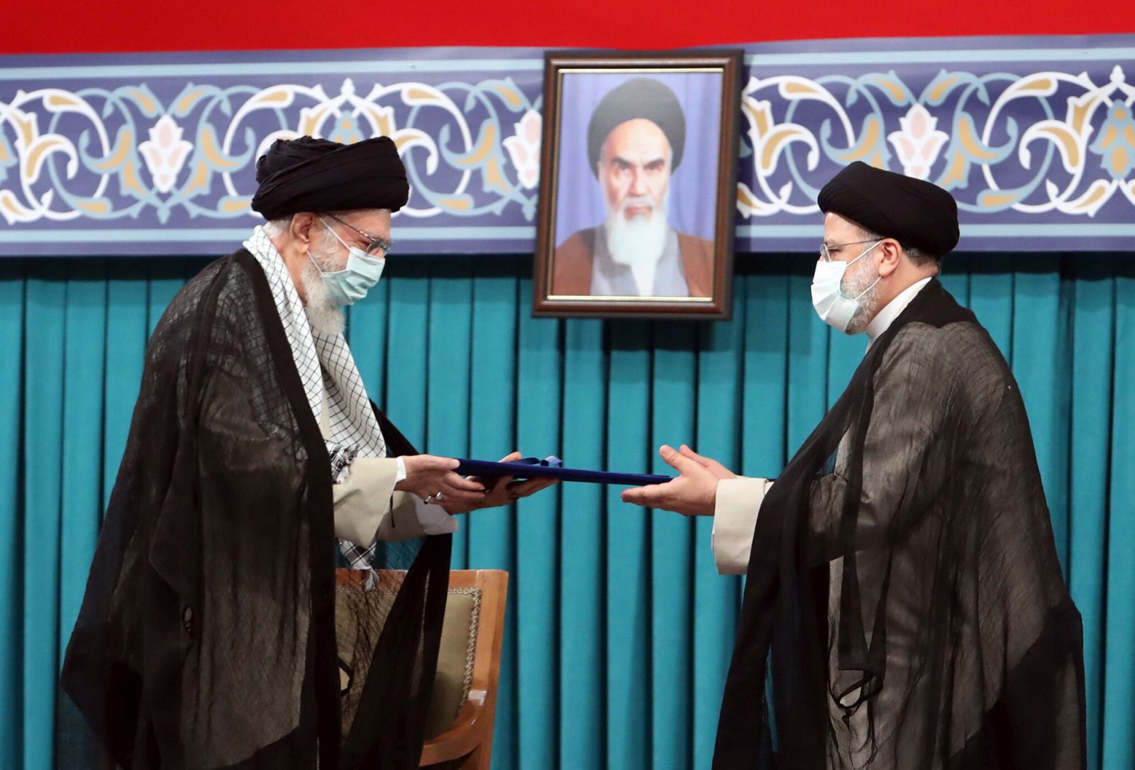 epa09389894 A handout picture made available by Iran's Supreme Leader Office shows Iranian supreme leader Ayatollah Ali khamenei (L) handing over the presidential precept to new Iranian president Ebrahim Raisi (R), in Tehran, Iran, 03 August 2021. Iranian presidents are first approved by the supreme leader, who according to constitution is the actual head of state, and then take the oath before parliament. Ebrahim Raisi has been inaugurated as the new president of the Islamic Republic of Iran on 03 August 2021, as the country is facing an economic crisis along with the coronavirus disease (COVID-19) pandemic.  EPA/IRAN'S SUPREME LEADER OFFICE HANDOUT  HANDOUT EDITORIAL USE ONLY/NO SALES
