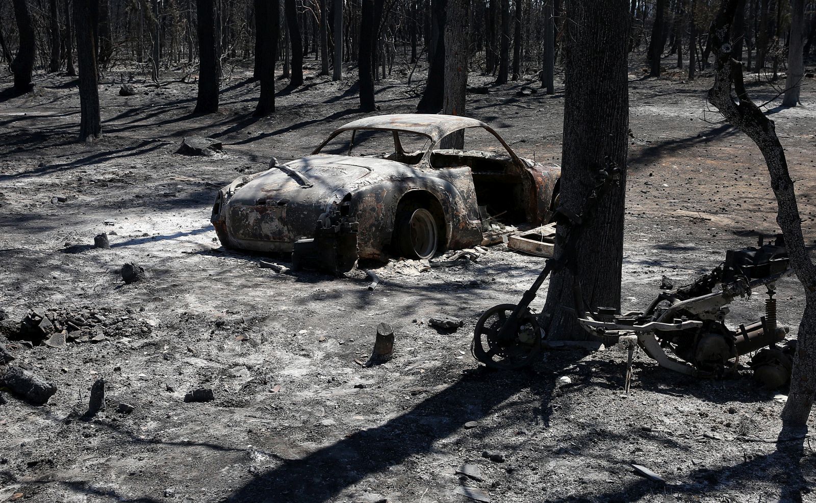 epa09406231 A burnt car is seen in the forest  in Varybobi area, near Athens, Greece, 08 August 2021. Fires that broke out in Attica and Evia island this week have burned more than a quarter of a million stremmas, the National Observatory of Athens' center Beyond said on August 08. Some 76,150 stremmas (7,615 hectares) have been burnt so far in northern Attica. At Evia island the surface area of burnt land is measured at 197,940 stremmas (19,794 hectares). These figures concern only the fires in Attica and Evia, but dozens of large fires have affected several areas across the country.  EPA/ORESTIS PANAGIOTOU