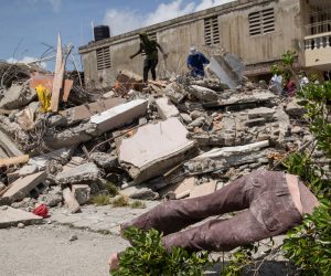 epa09419411 Some men walk on and search the rubble of a building, after the earthquake of August 14, in Les Cayes, Haiti, 18 August 2021. The 7.2 magnitude earthquake registered last 14 August in Haiti and which mainly hit the South department, whose capital is Les Cayes, caused serious material damage, at least 1,941 dead and 9,900 injured.  EPA/Orlando Barria