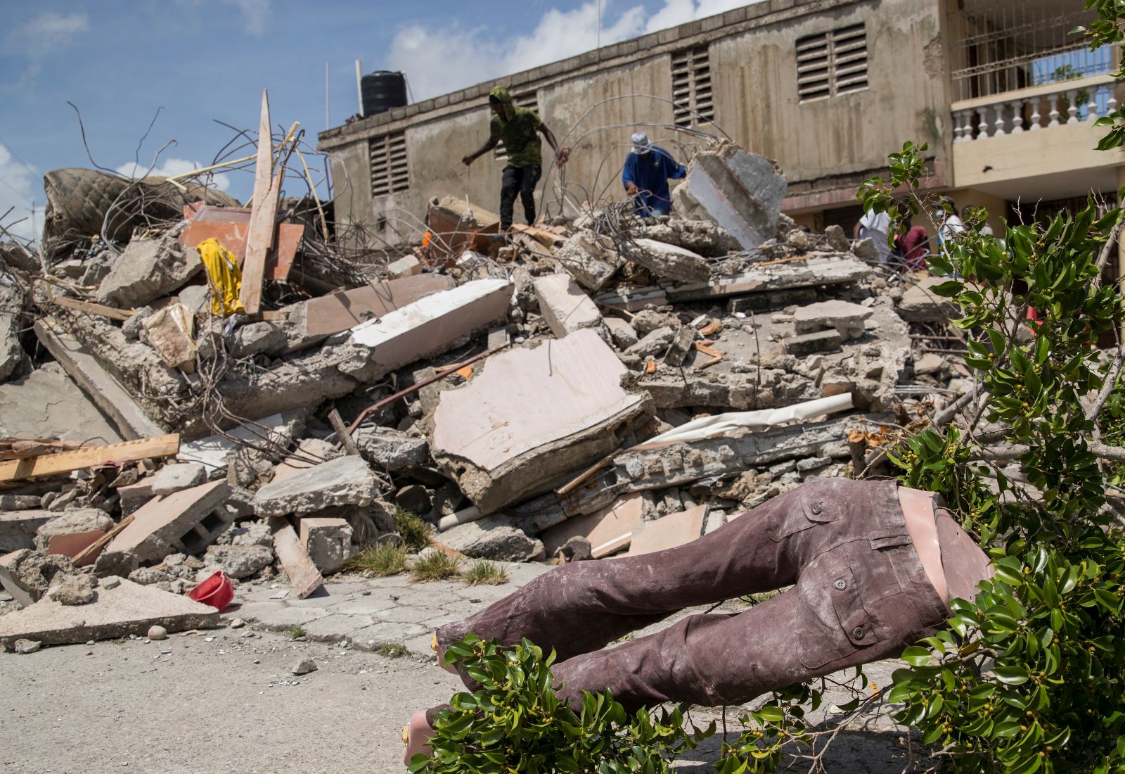 epa09419411 Some men walk on and search the rubble of a building, after the earthquake of August 14, in Les Cayes, Haiti, 18 August 2021. The 7.2 magnitude earthquake registered last 14 August in Haiti and which mainly hit the South department, whose capital is Les Cayes, caused serious material damage, at least 1,941 dead and 9,900 injured.  EPA/Orlando Barria