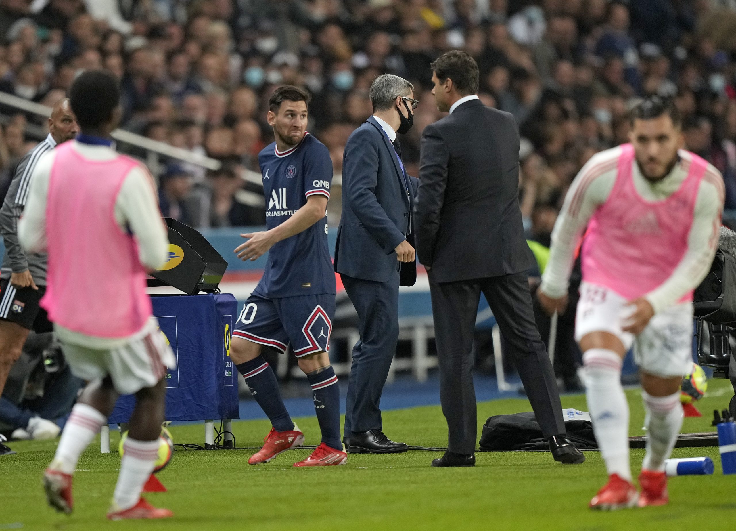 PSG's Lionel Messi looks at PSG's head coach Mauricio Pochettino after he was substituted during the French League One soccer match between Paris Saint-Germain and Lyon at the Parc des Princes in Paris Sunday, Sept. 19, 2021. (AP Photo/Francois Mori)