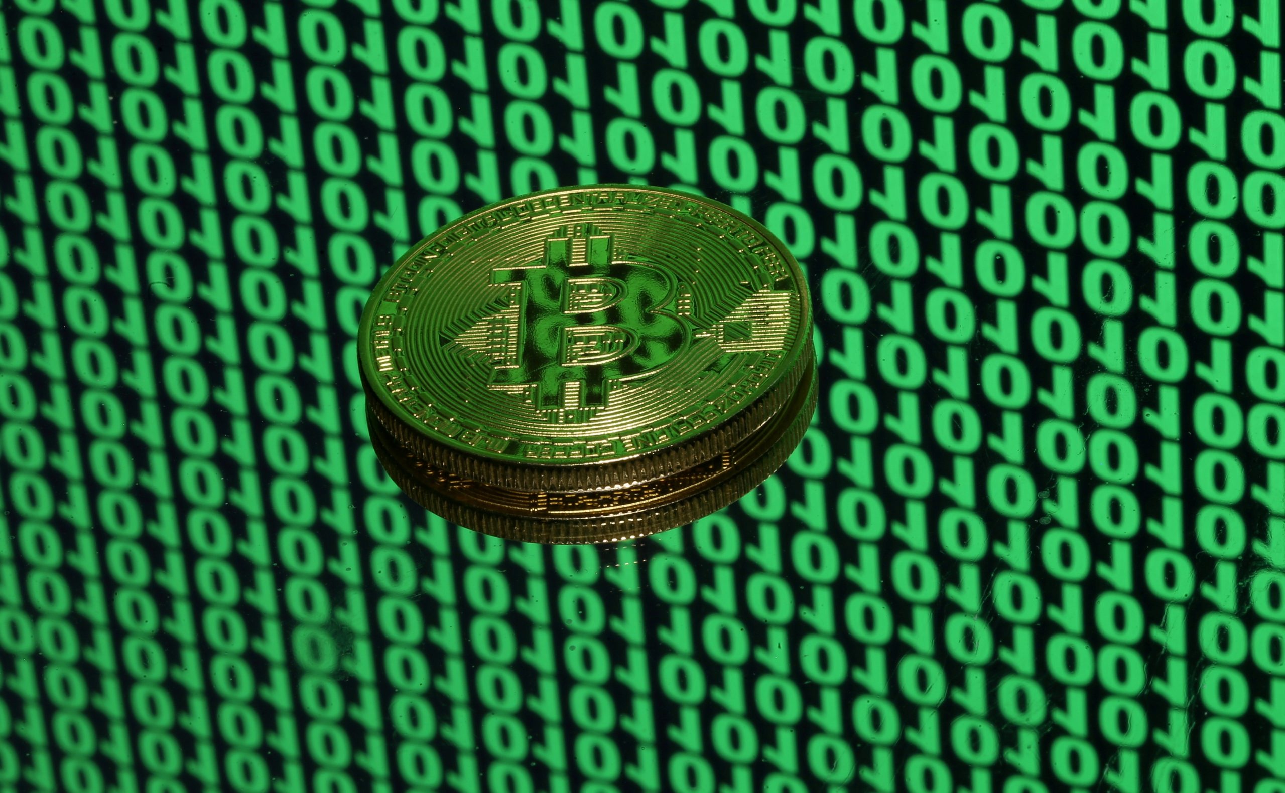 FILE PHOTO: Bitcoin token is seen placed on a monitor that displays binary digits in this illustration picture FILE PHOTO: A token of the virtual currency Bitcoin is seen placed on a monitor that displays binary digits in this illustration picture, December 8, 2017. REUTERS/Dado Ruvic/Illustration/File Photo Dado Ruvic