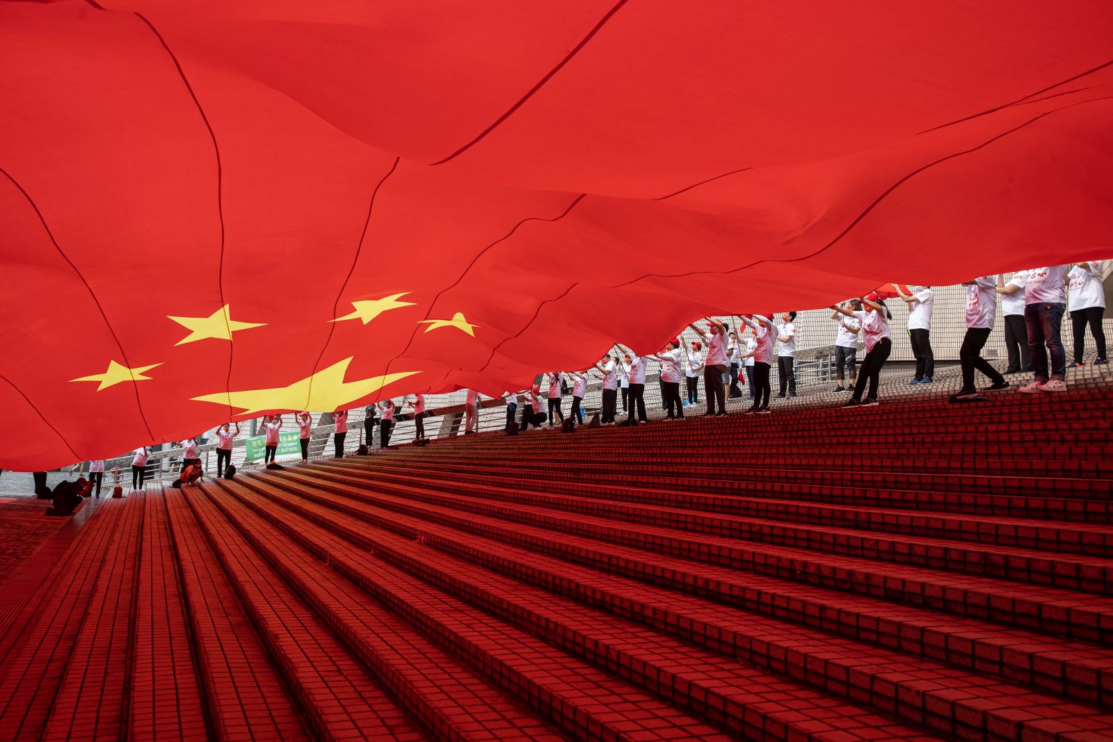 epaselect epa09499004 People display a huge Chinese flag during a ceremony celebrating China's National Day at the waterfront of the Victoria Harbour in Hong Kong, China, 01 October 2021. China celebrates its National Day on 01 October 2021, marking the 72nd founding anniversary of the People's Republic of China.  EPA/JEROME FAVRE