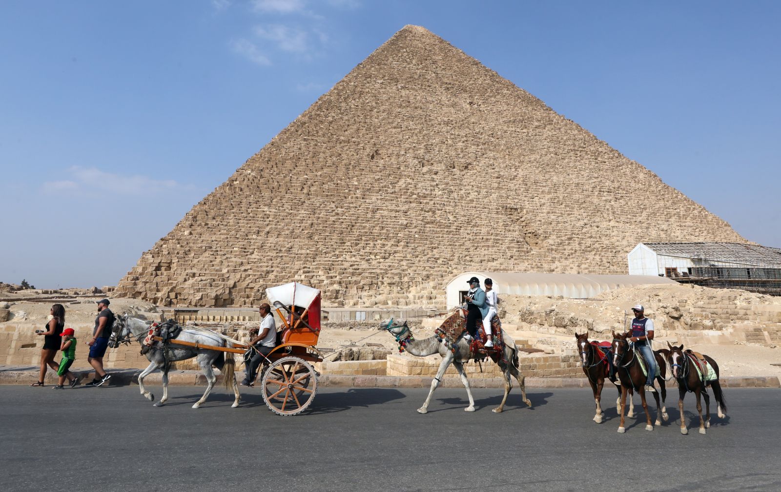 epa09502835 People ride camels past the pyramids in Giza, Egypt, 02 October 2021  EPA/KHALED ELFIQI