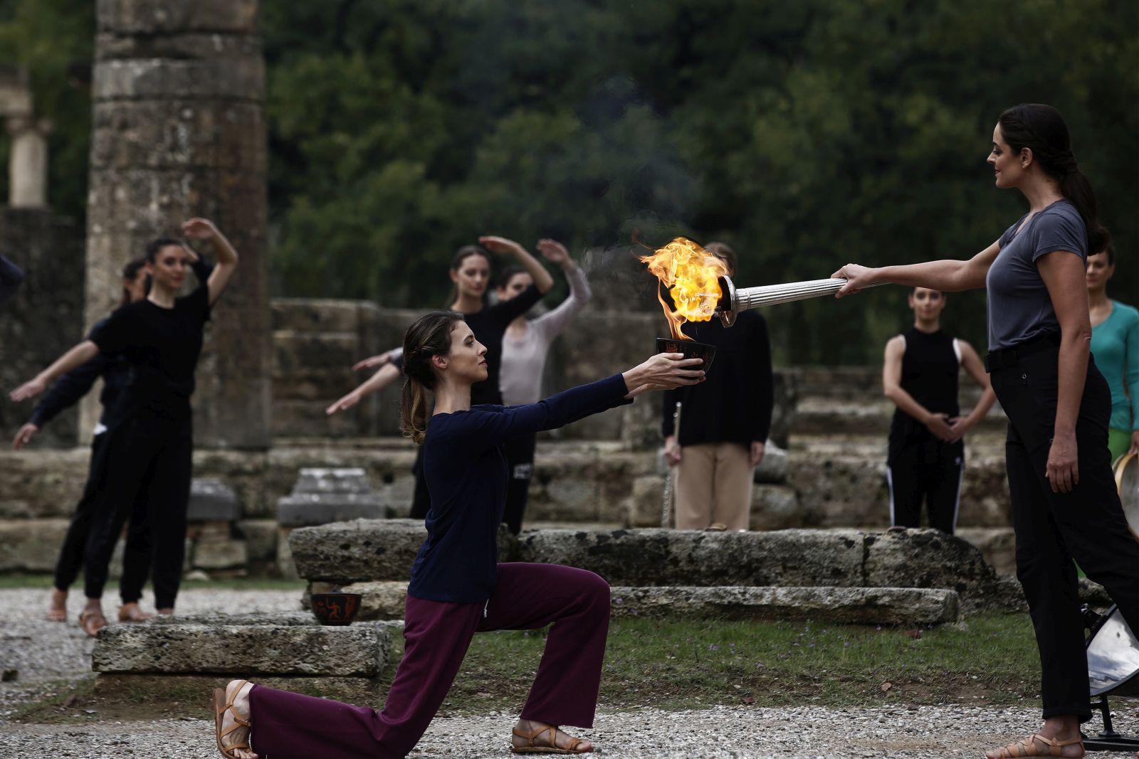 epa09528355 Greek actress Xanthi Georgiou (R), playing the role of High Priestess, lights the flame during the rehearsal of the Olympic flame lighting ceremony for the Beijing 2022 Winter Olympics, at the Ancient Olympia site, in southern Greece, 17 October 2021.  EPA/YANNIS KOLESIDIS