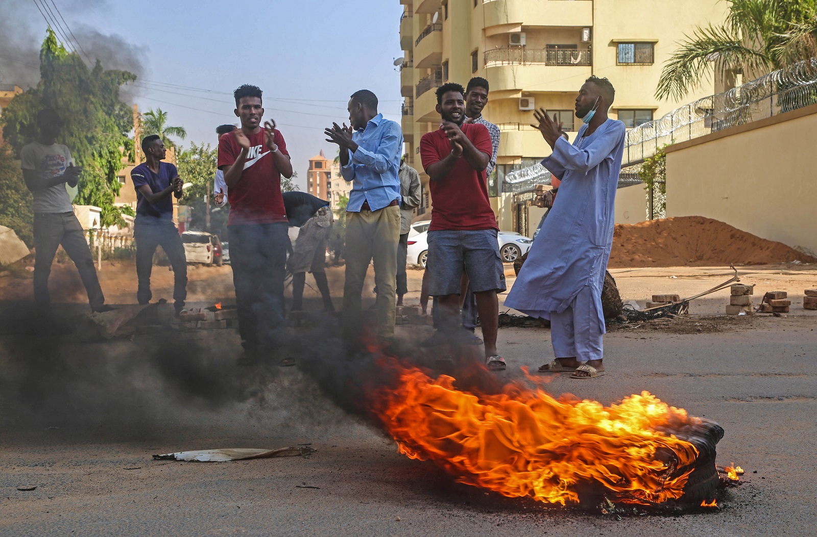 epa09545014 Sudanese protester chant near burning tires during a demonstration in the capital Khartoum, Sudan 25 October 2021. Sudan's military launched a coup attempt, and arrested the Prime Minister Abdalla Hamdok and other senior ministers and civilian members of the Transitional Sovereignty Council during early morning raids, as thousands of people gather for protest the attempt in the capital, Khartoum.  EPA/MOHAMMED ABU OBAID