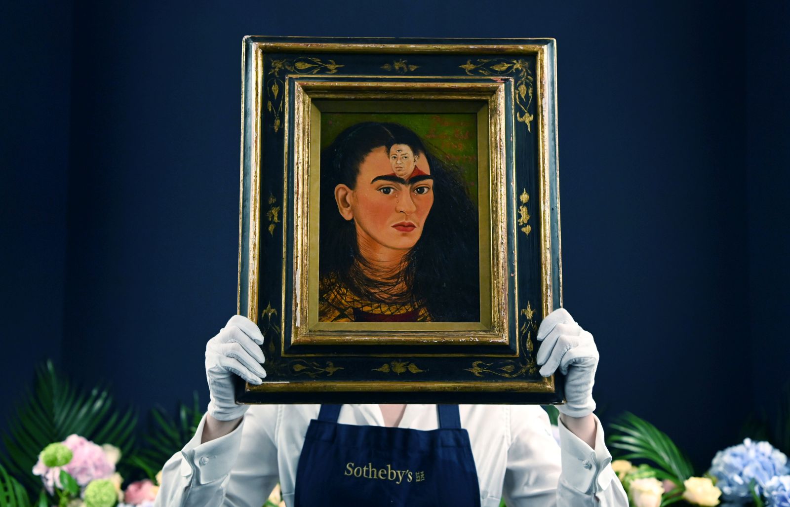 epa09535655 A Sotheby's auction house staff with Mexican artist Frida Kahlo's final 'bust' self-portrait, titled 'Diego y yo' (Diego and I), at Sotheby's in London, Britain, 21 October, 2021. Thought to be the most valuable work by the Mexican artist, the painting is estimated to fetch in excess of some USD 30 million and will go on sale in New York in November.  EPA/ANDY RAIN
