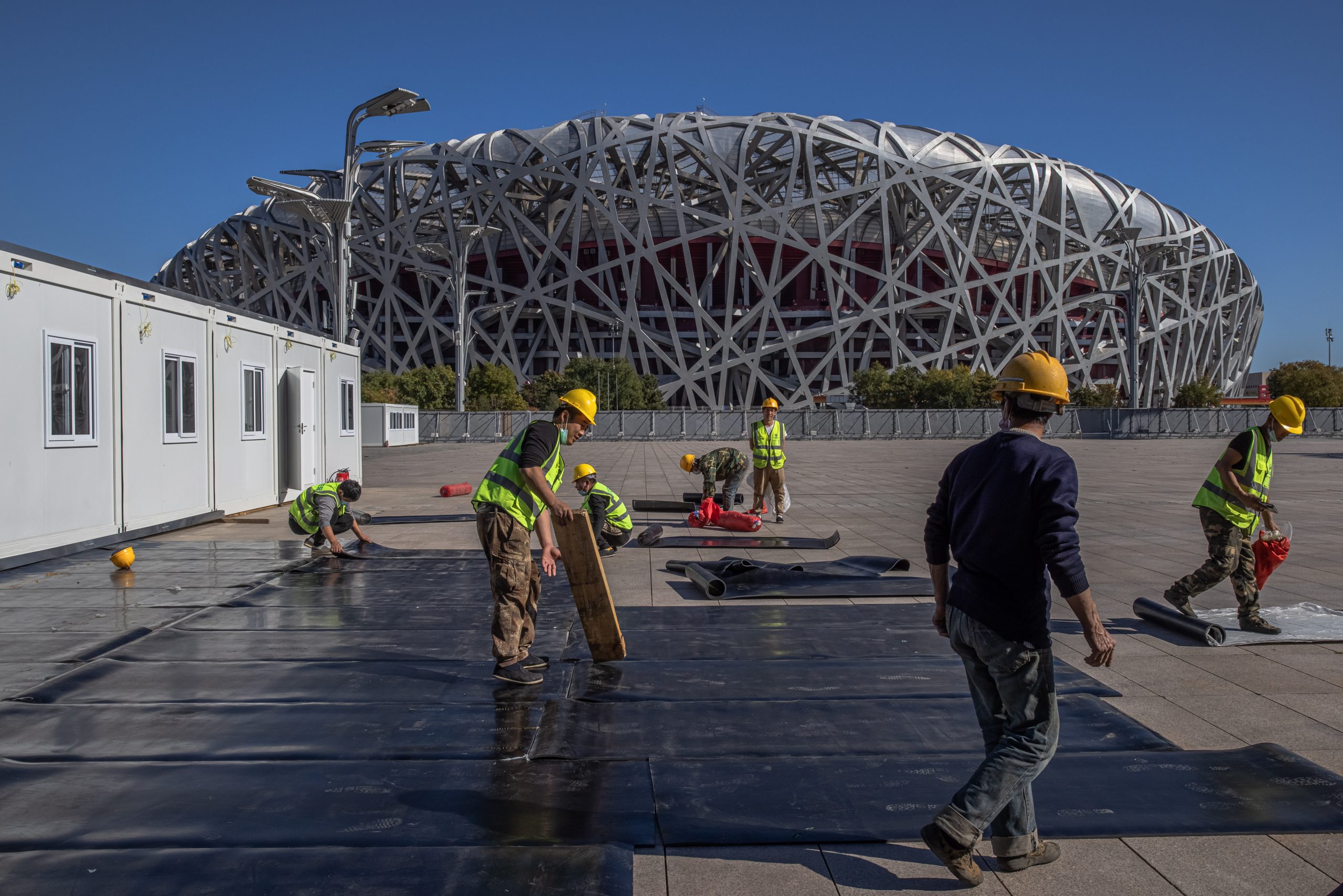 epa09548186 Employees work in front of the National Stadium, also known as Bird's Nest which is scheduled to be used for the opening and closing ceremonies of 2022 Beijing Winter Olympics and 2022 Winter Paralympics, 100 days before the 2022 Beijing Winter Olympics, in Beijing, China, 27 October 2021. The 2022 Beijing Winter Olympics is scheduled to take place in 100 days from 04 to 20 February 2022, and the Paralympics from 04 March to 13 March 2022.  EPA/ROMAN PILIPEY