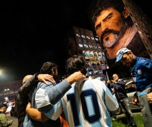 epa09555570 Fans celebrate Diego Armando Maradona's birthday anniversary next to a mural, made by Italian-Dutch street artist Jorit, depicting the late Argentine football legend in Naples, southern Italy, late 30 October 2021. Maradona passed away on 25 November 2020 at the age of 60.  EPA/CESARE ABBATE