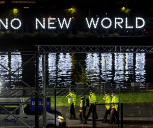 epa09556393 Police walk past the media centre as a sign flashes a message reading ' No New World'  in Glasgow, Britain, 31 October 2021. COP26 events will take place across two venues the Blue Zone at the Scottish Event Campus and the Green Zone at Glasgow Science Centre.  EPA/Robert Perry