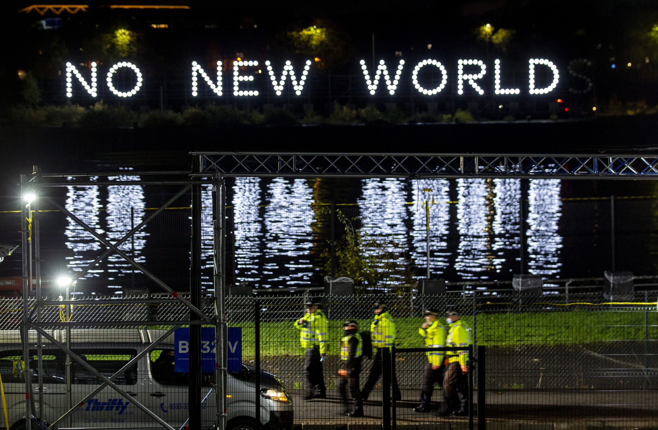 epa09556393 Police walk past the media centre as a sign flashes a message reading ' No New World'  in Glasgow, Britain, 31 October 2021. COP26 events will take place across two venues the Blue Zone at the Scottish Event Campus and the Green Zone at Glasgow Science Centre.  EPA/Robert Perry