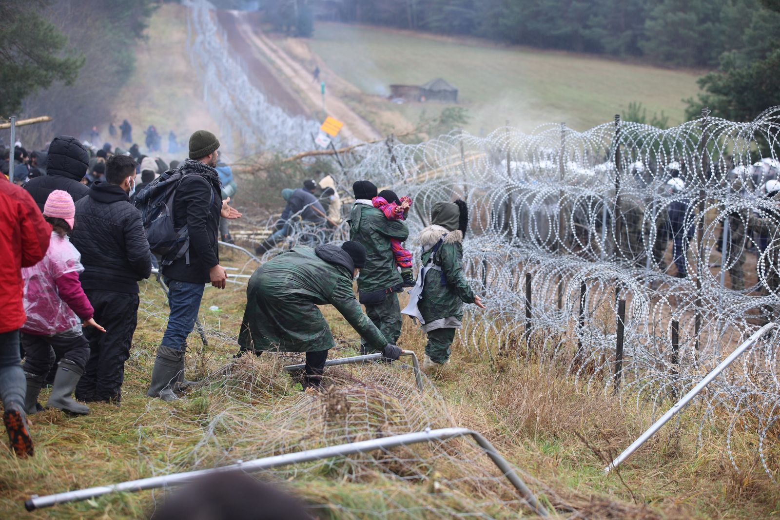 epa09572057 A handout photo made available by Belta news agency shows migrants clashing with authorities on the Belarusian-Polish border in the Grodno region, Belarus, 08 November 2021 (issued 09 November 2021). According to the State Border Committee of Belarus, there are more than two thousand people near the border, including women and children, who want to obtain asylum in the European Union, 'and they do not consider the territory of the Republic of Belarus as a place of stay.' Against this background, the Polish authorities announced preparations for a breakthrough across the border. The territory is guarded by several thousand employees of the Polish special services. The migration crisis at the border of Belarus has been going on since the spring of 2021. Belarus President Alexander Lukashenko said that after the introduction of new EU sanctions against Minsk, the Belarusian authorities will no longer interfere with the movement of illegal migrants to the European Union.  EPA/LEONID SCHEGLOV / HANDOUT  HANDOUT EDITORIAL USE ONLY/NO SALES