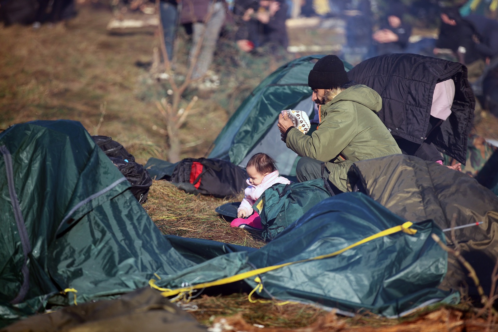 epa09572488 A handout picture made available by Belta news agency shows migrants at their camp near the Belarus-Polish border in the Grodno region, Belarus, 09 November 2021. According to the State Border Committee of Belarus (GPK), there are more than two thousand people near the border, including women and children, who want to obtain asylum in the European Union, 'and they do not consider the territory of the Republic of Belarus as a place of stay.' The territory is guarded by several thousand employees of the Polish special services. The migration crisis at the border of Belarus has been going on since the spring of 2021. Belarusian President Lukashenko said that after the introduction of new EU sanctions against Minsk, the Belarusian authorities will no longer interfere with the movement of illegal migrants to the European Union.  EPA/LEONID SCHEGLOV/BELTA HANDOUT  HANDOUT EDITORIAL USE ONLY/NO SALES