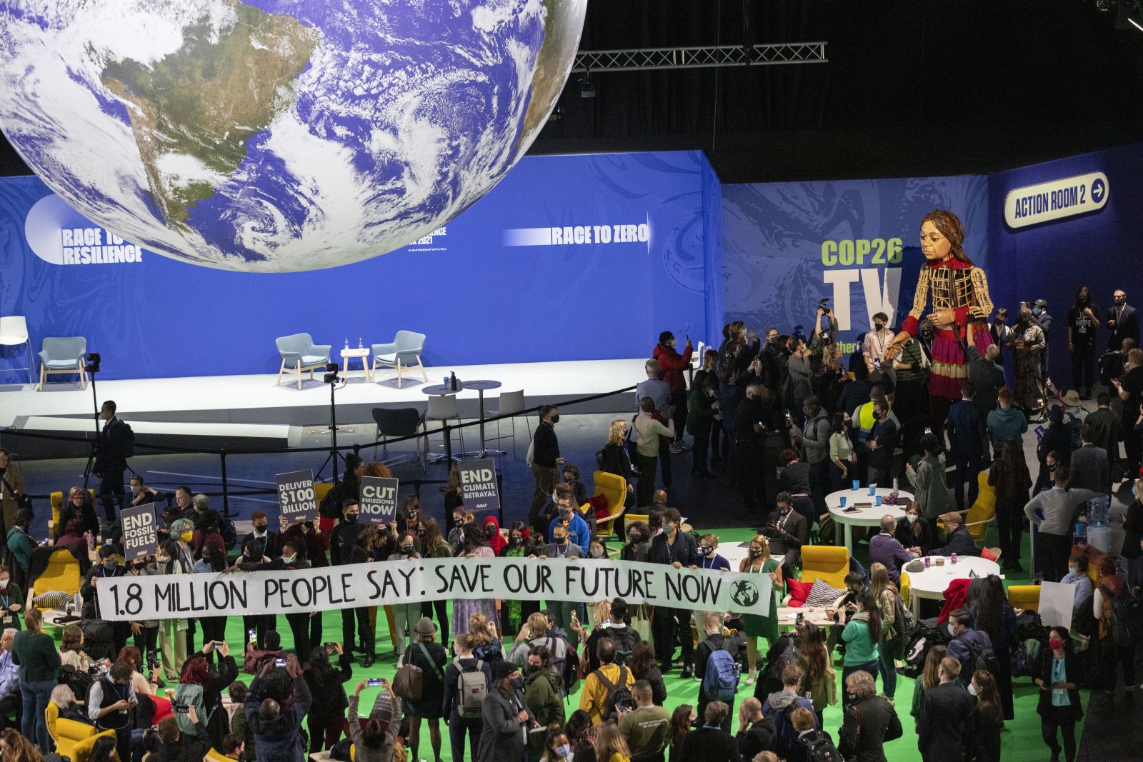 epa09572554 Delegates and participants gather around Little Amal (C), in the Hydro during the COP26 UN Climate Summit in Glasgow, Britain, 09 November 2021. Little Amal is the giant puppet of a 3.5 metre-tall living artwork of a young Syrian refugee child on 'The Walk', travelling 8,000km in 2021 in support of refugees across Turkey, Greece, Italy, France, Switzerland, Germany, Belgium and the UK to focus attention on the urgent needs of young refugees. The 2021 United Nations Climate Change Conference (COP26) runs from 31 October to 12 November 2021 in Glasgow.  EPA/ROBERT PERRY