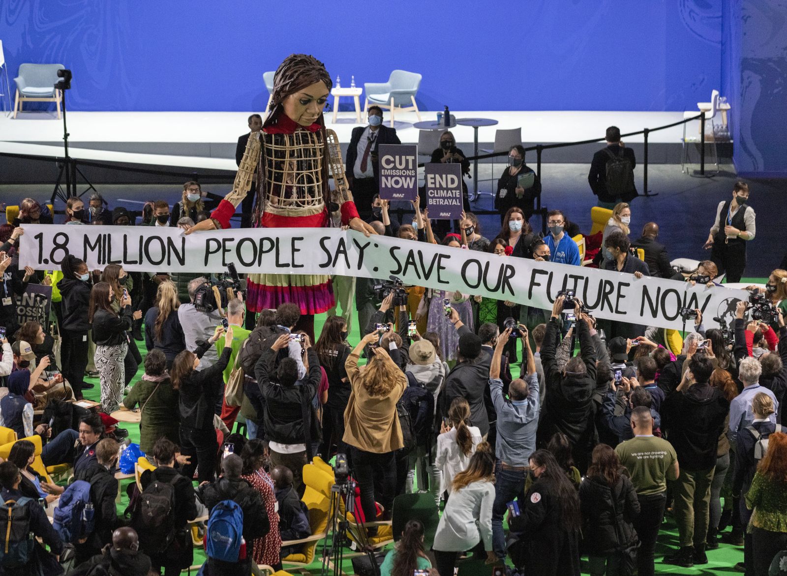 epa09572558 Delegates and participants gather around Little Amal (C), in the Hydro during the COP26 UN Climate Summit in Glasgow, Britain, 09 November 2021. Little Amal is the giant puppet of a 3.5 metre-tall living artwork of a young Syrian refugee child on 'The Walk', travelling 8,000km in 2021 in support of refugees across Turkey, Greece, Italy, France, Switzerland, Germany, Belgium and the UK to focus attention on the urgent needs of young refugees. The 2021 United Nations Climate Change Conference (COP26) runs from 31 October to 12 November 2021 in Glasgow.  EPA/ROBERT PERRY