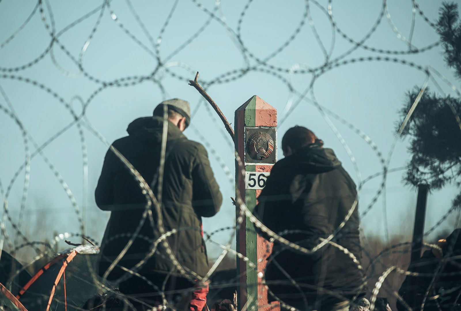 epa09578274 A handout photo made available by Polish Territorial Defence Force shows migrants behind the border fence in Belarus near the Polish-Belarusian border crossing in Kuznica, eastern Poland, 09 November 2021 (issued 12 November 2021). According to Polish Border Guard, over a thousand refugees, who want to obtain asylum in the European Union have been trapped at low temperatures at the border Polish-Belarusian border.  EPA/IREK DOROZANSKI / POLISH TERRITORIAL DEFENCE FORCE / HANDOUT POLAND OUT HANDOUT EDITORIAL USE ONLY/NO SALES