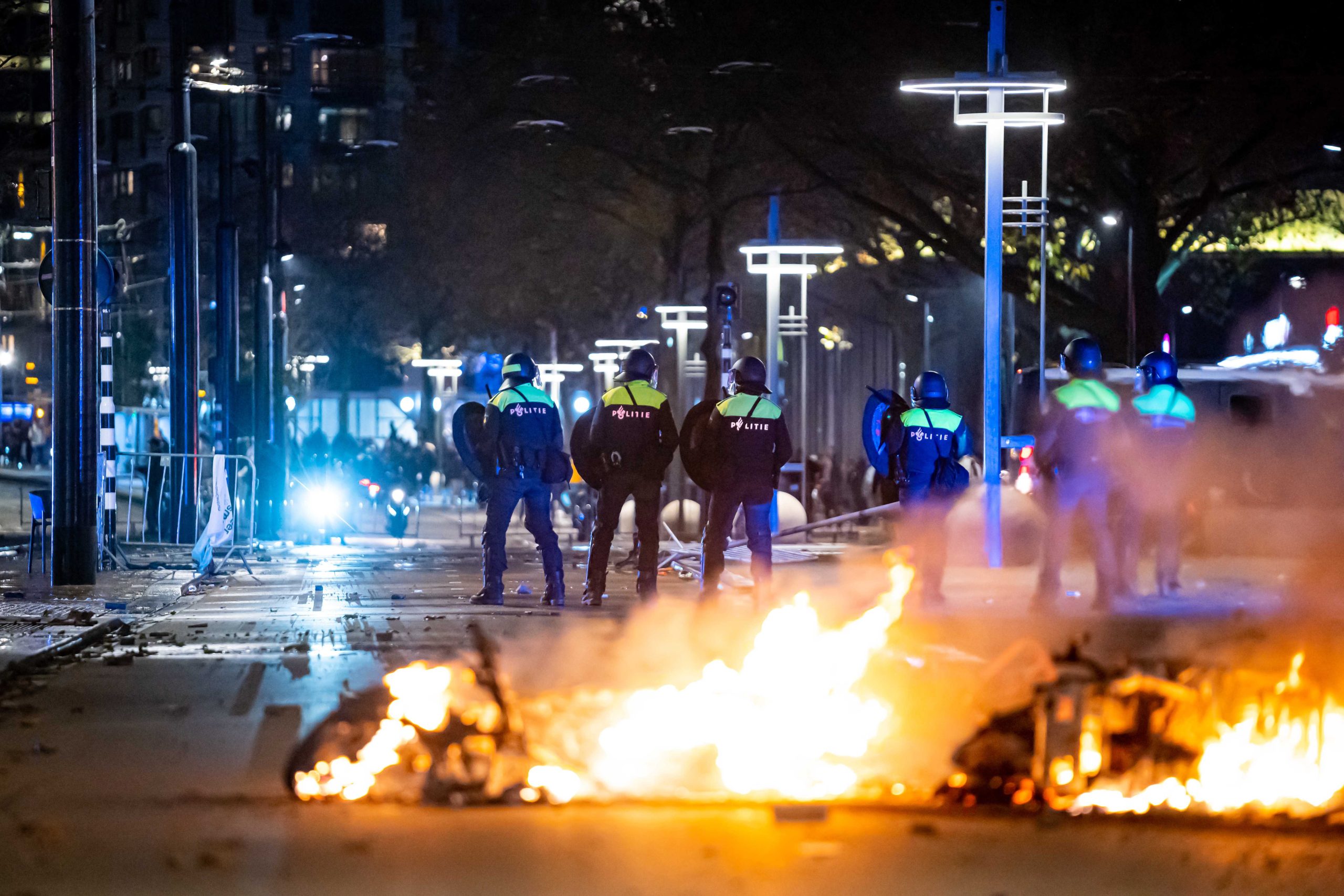 epaselect epa09593019 Policemen stand near burning objects after a protest against the '2G policy' turned into riots, with protesters setting fires in the street and destroying police cars and street furniture, Rotterdam, Netherlands, 19 November 2021. Hundreds of demonstrators gathered on Coolsingel earlier that evening because they disagree with the 2G policy, which refers to the two Dutch words for vaccinated and recovered.  EPA/VLN NIEUWS
