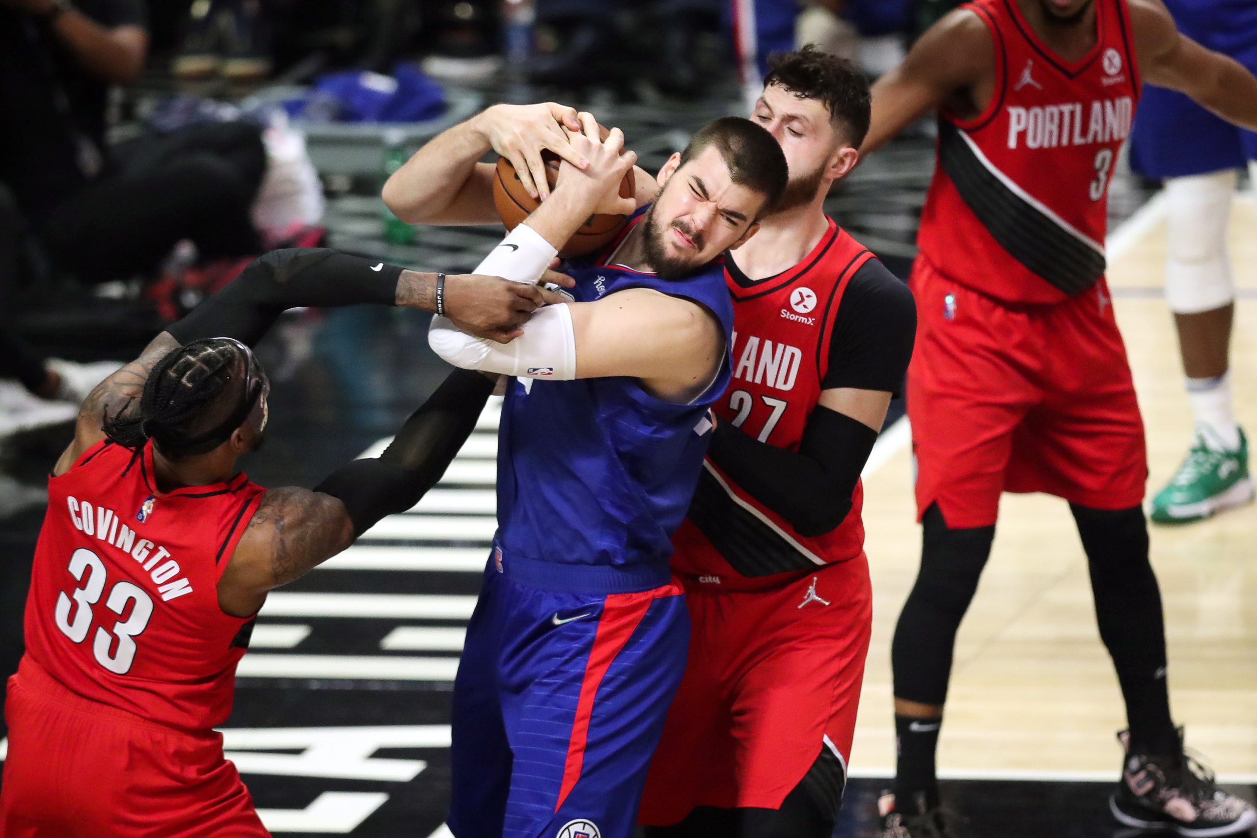 epa09573370 Los Angeles Clippers center Ivica Zubac (C-L) holds onto the ball while being guarded by Portland Trail Blazers forward Robert Covington (L) and Portland Trail Blazers center Jusuf Nurkic (R) during the second quarter of the NBA basketball game between the Los Angeles Clippers and Portland Trail Blazers at the Staples Center in Los Angeles, California, USA, 09 November 2021.  EPA/CAROLINE BREHMAN  SHUTTERSTOCK OUT