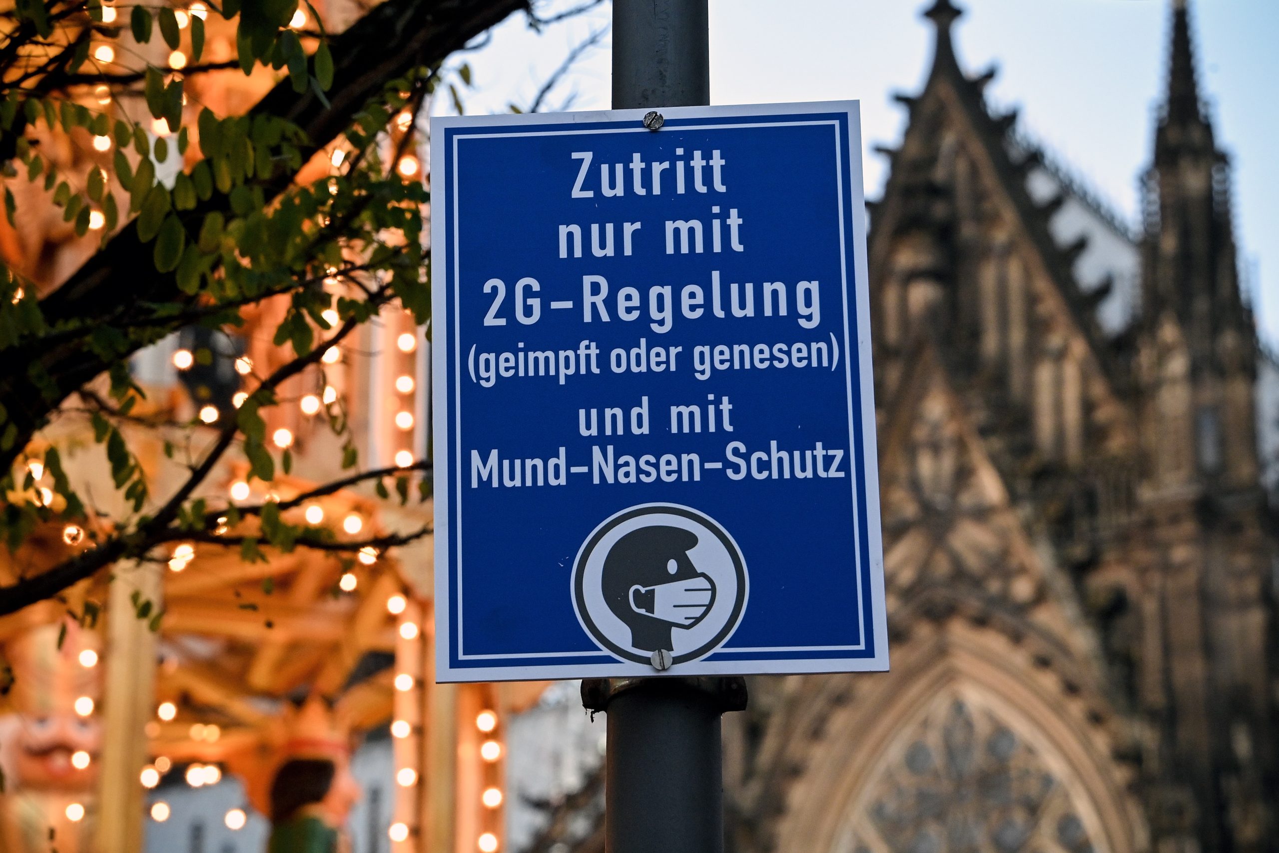 epa09597962 An information sign reading, 'Access according to 2G rule: vaccinated, recovered', placed at the entrance of the Christmas market in Cologne, Germany, 22 November 2021. Germany is dealing with a high number of new coronavirus COVID-19 infections.  EPA/SASCHA STEINBACH