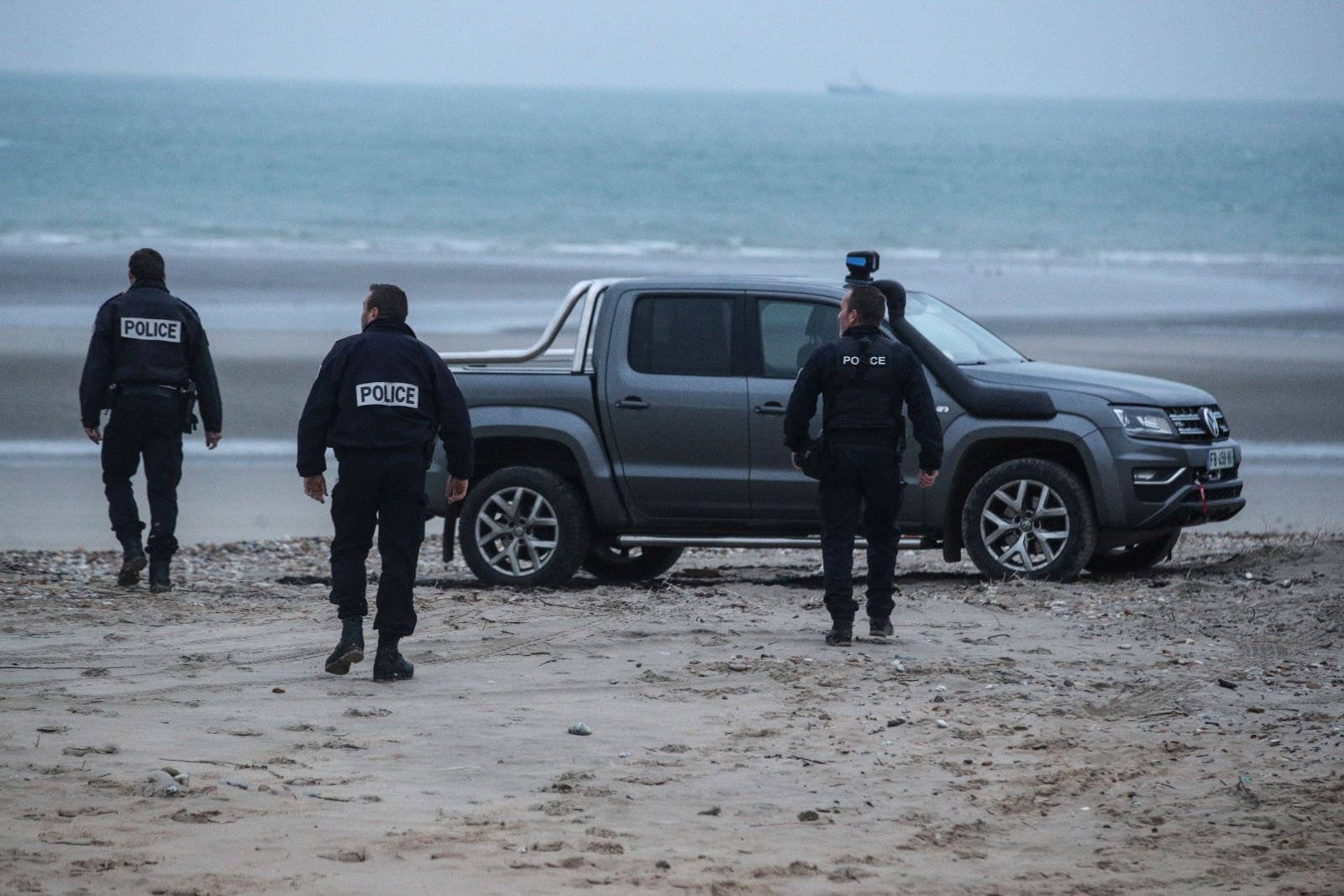 epa09602233 Policemen inspect the beach near Wimereux, France, 25 November 2021. At least 27 migrants have died and two others have been taken to hospital after a boat in which they were trying to cross the La Manche canal (English Channel) to Great Britain sank on 24 November.  EPA/MOHAMMED BADRA