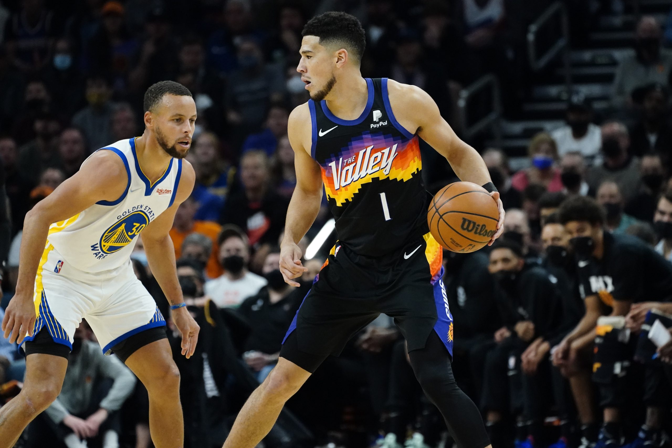 Phoenix Suns guard Devin Booker (1) defended by Golden State Warriors guard Stephen Curry (30) during the first half of an NBA basketball game, Tuesday, Nov. 30, 2021, in Phoenix. (AP Photo/Matt York)