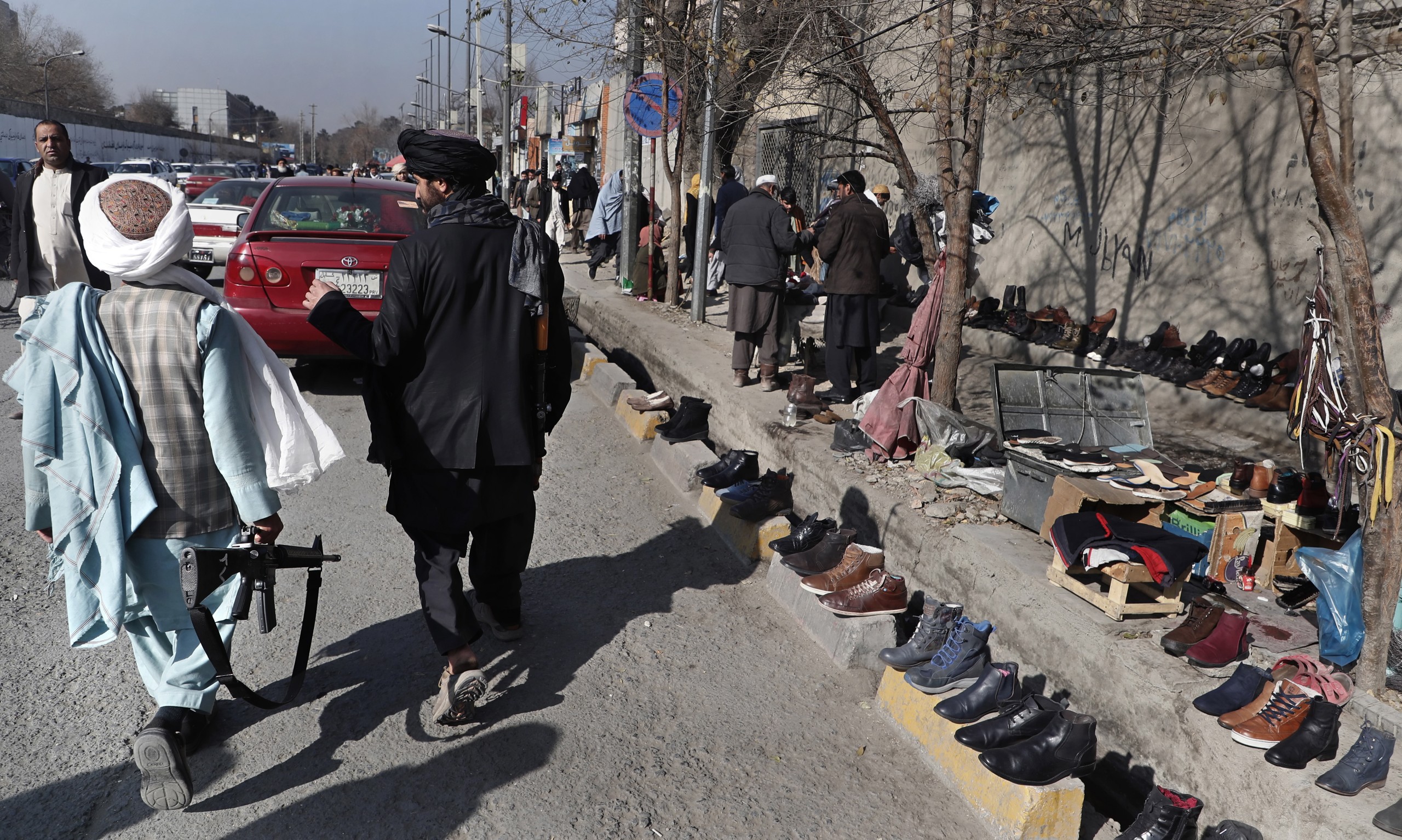 epa09638702 Taliban members patrol a second-hand shoes street market as seller waits for customers in downtown Kabul, Afghanistan, 12 December 2021. The Taliban has said that the United Nations should help them in assisting nearly 3.5 million Afghans return to their homes after having been displaced inside the country due to violence.  EPA/MAXIM SHIPENKOV
