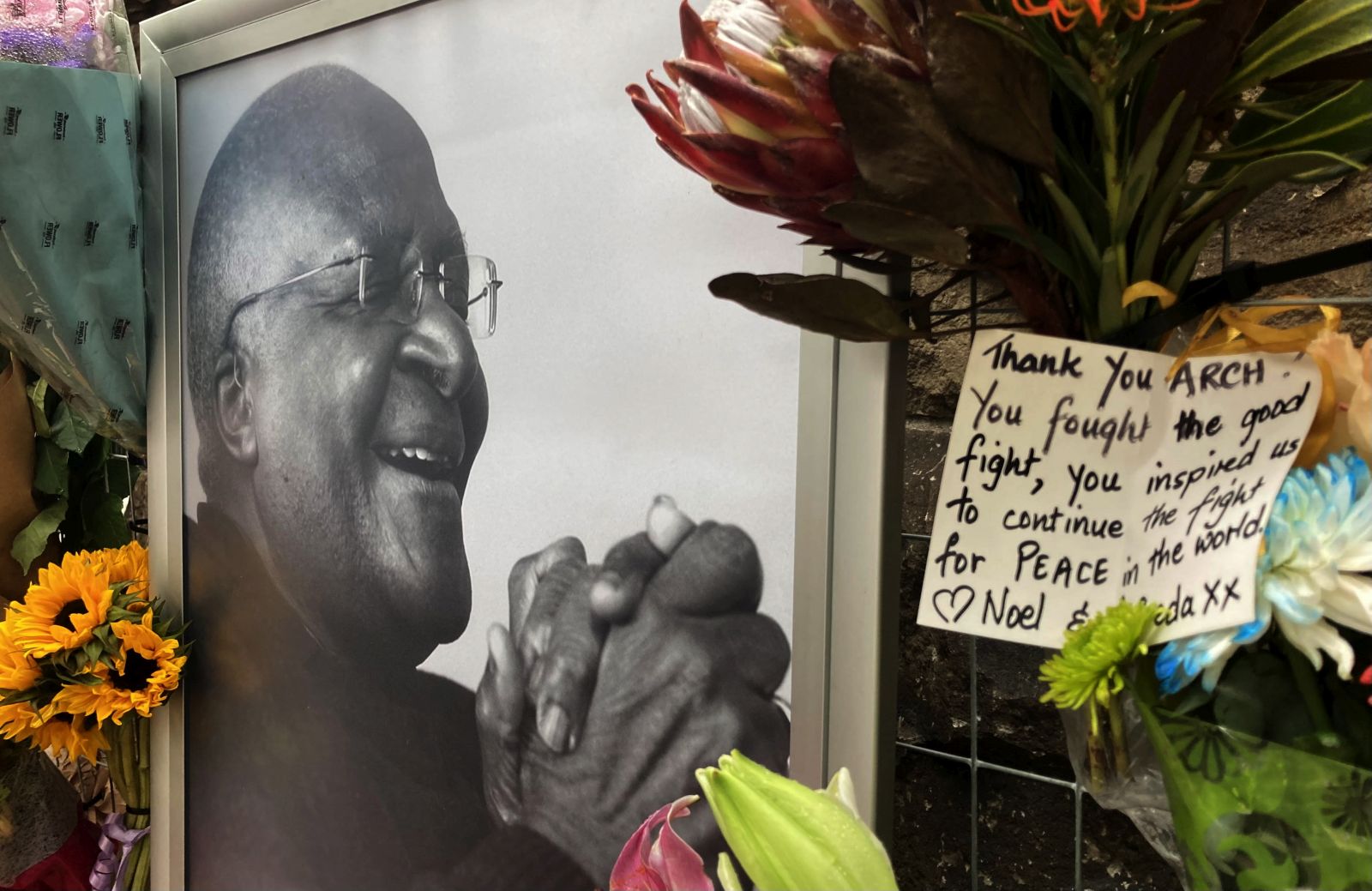 epa09657702 Flowers are seen in front of a photograph of the late Archbishop Emeritus Desmond Tutu at the St Georges Cathedral , Cape Town, South Africa, 27 December 2021. The anti apartheid activist and Nobel Peace Price winner died aged 90 at a frail care home. There will be a 7 day send-off including a state funeral, lying in state and church service at his old church.  EPA/STR