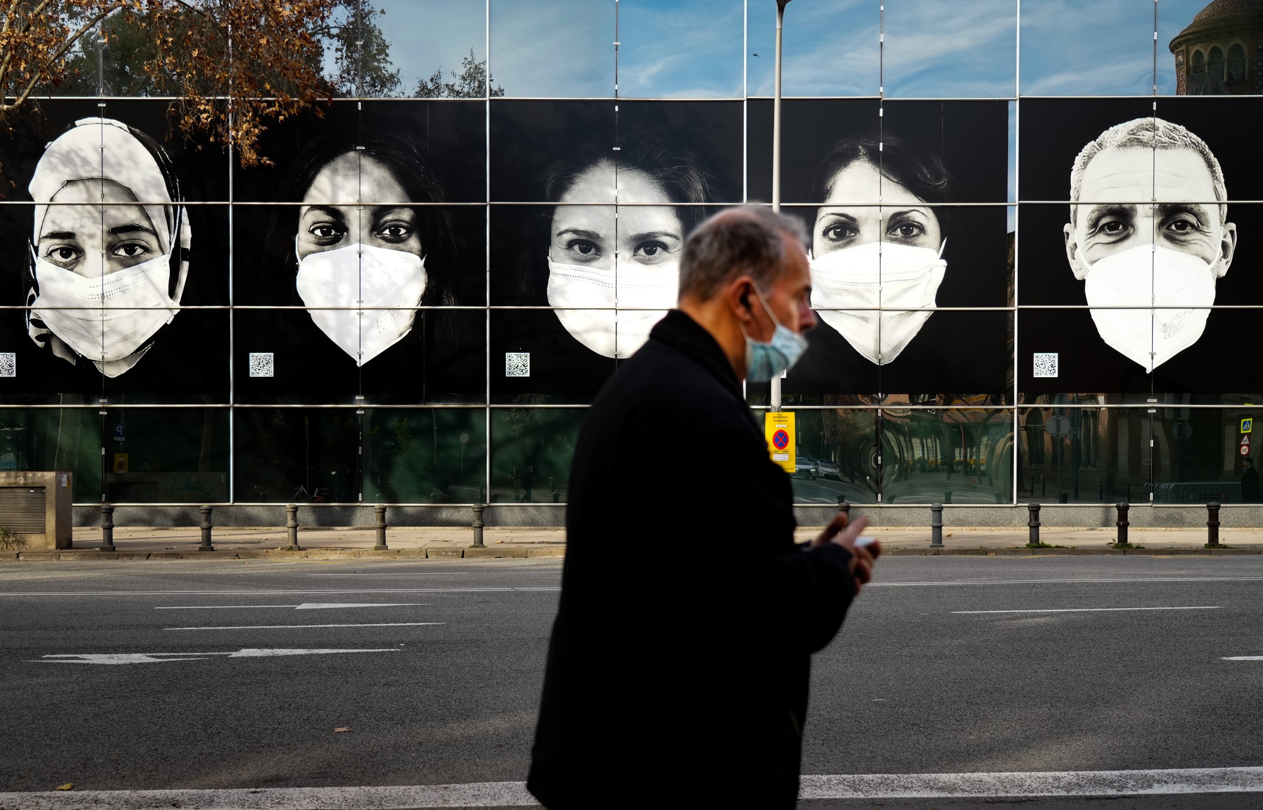 epa09657136 A man walks past a vaccination center in Barcelona, north-eastern Spain, 26 December 2021. As the omicron variant hit Spain, the government concluded this week that masks outdoors were the solution.  EPA/Enric Fontcuberta
