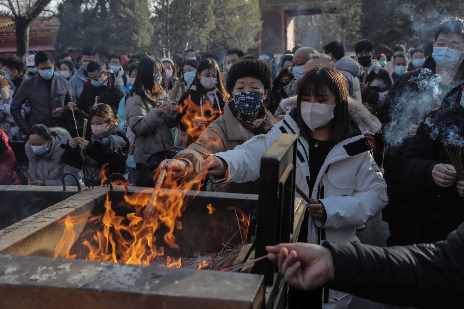 epa09662333 People gather to burn incense sticks while praying for good wishes on New Year's Day at the Yonghegong Lama Temple in Beijing, China, 01 January 2022. Many cities in China canceled New Year's Eve celebrations amid rising concerns over the coronavirus disease (COVID-19) pandemic.  EPA/WU HONG