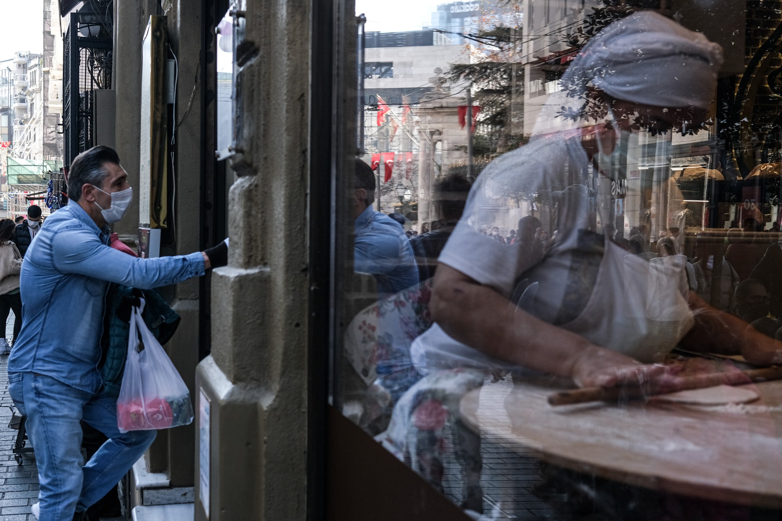 epa09668002 A woman wearing face mask (R) knits bread in Istiklal Street in Istanbul, Turkey, 05 January 2022. In Turkey, there have been 9,596,779 confirmed cases of COVID-19 with 82,795 deaths, the World Health Organization (WHO) reported. According to the weekly data of cases by provinces shared by Minister of Health Koca, the number of COVID-19 cases per 100 thousand people was 303.51 in Istanbul in the week of 18 to 24 December 2021.  EPA/SEDAT SUNA