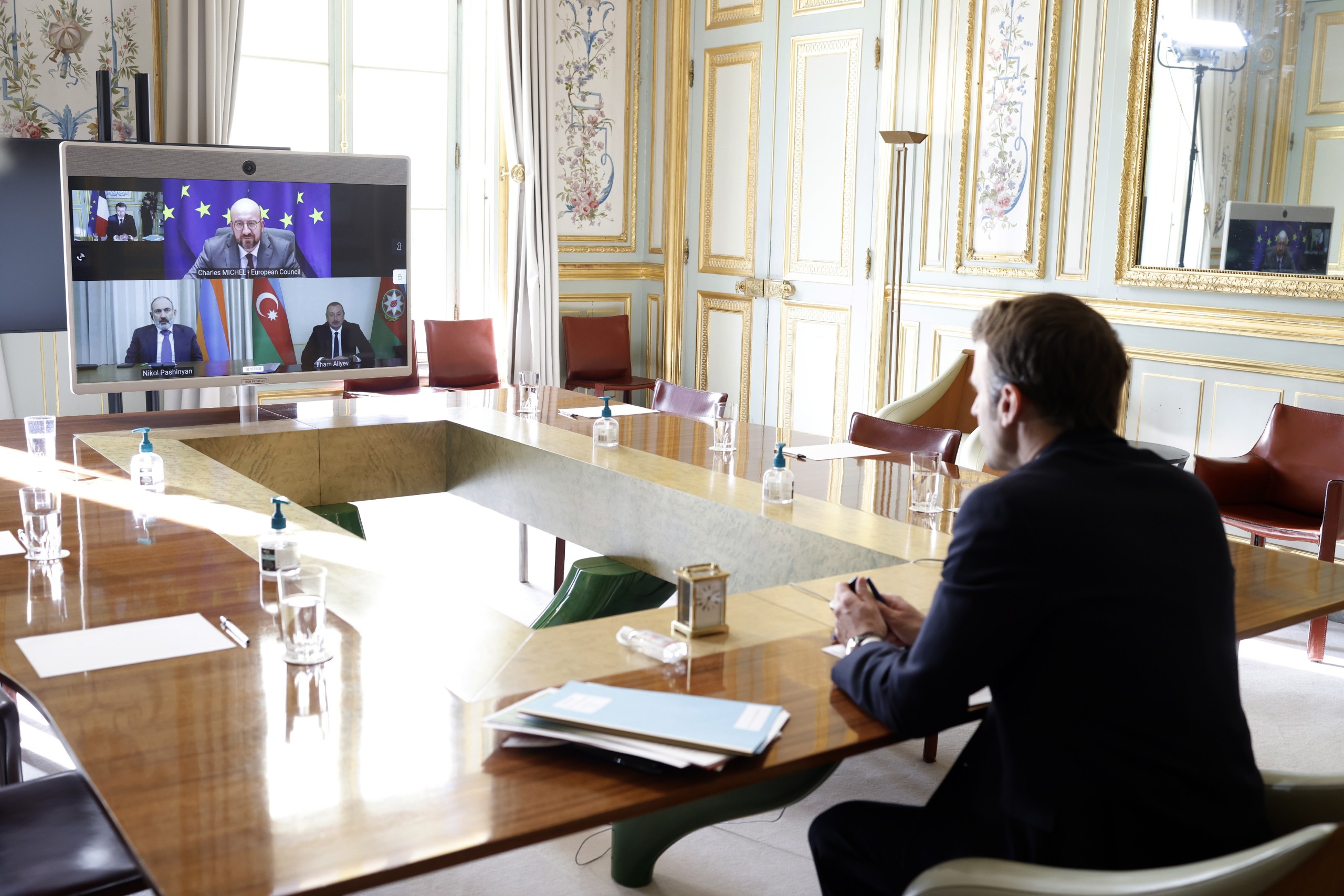 epa09727524 French President Emmanuel Macron (L) holds a video conference meeting with Armenian Prime Minister Nikol Pachinian (screen, L), Azerbaijan President Ilham Aliev (screen, R) and European Council President Charles Michel (screen, up) at the Elysee Palace in Paris, France, 04 February 2022.  EPA/YOAN VALAT / POOL