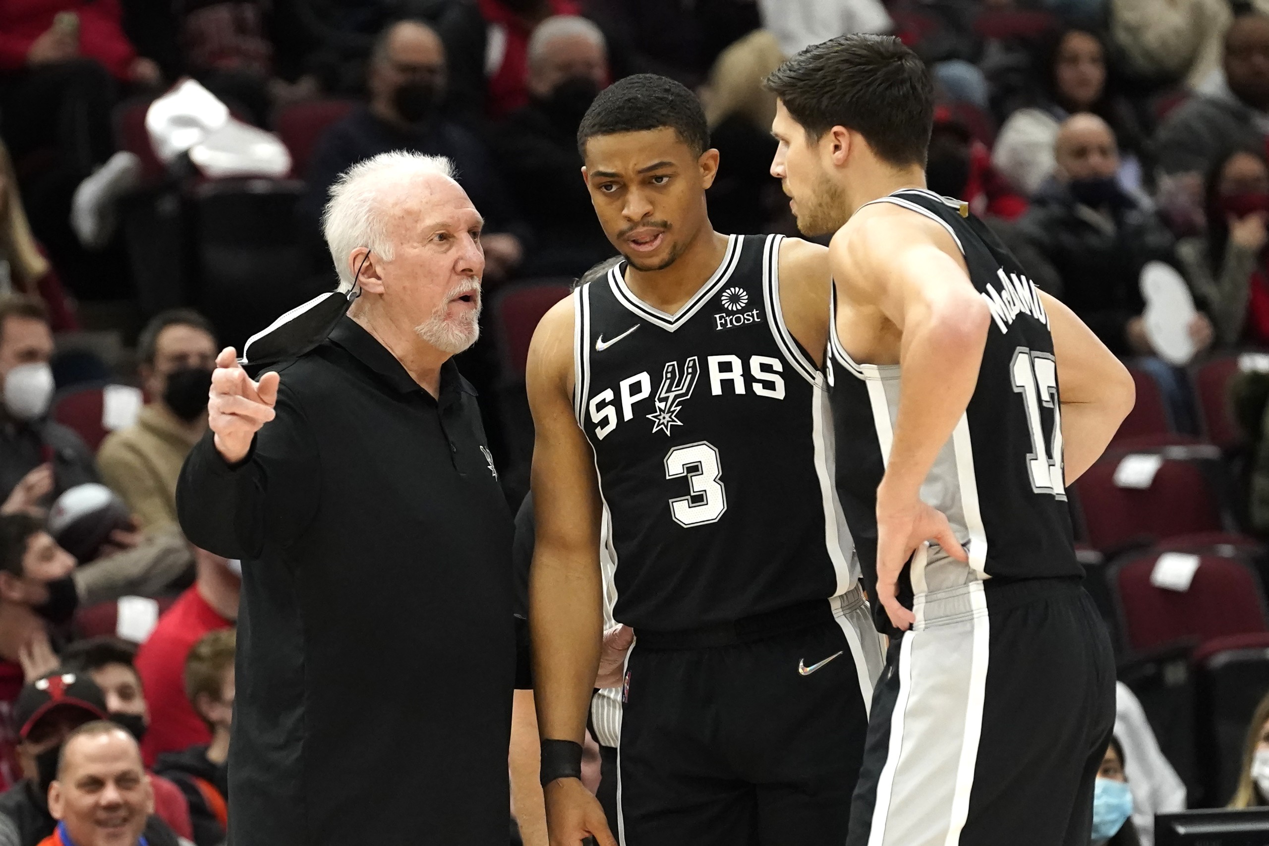 San Antonio Spurs head coach Gregg Popovich, left, talks with forward Keldon Johnson (3) and Doug McDermott during the first half of an NBA basketball game against the Chicago Bulls, Monday, Feb. 14, 2022, in Chicago. (AP Photo/Charles Rex Arbogast)