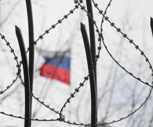 epaselect epa09775496 A Russian flag is seen behind a barbwire on a fence of the Russian Embassy during the performance of the Ukrainian and Crimean Tatar activists in Kiev, 21 February 2022. Eleven broken doors were installed as a symbol of 11 broken lives of civic journalists and Crimean Tatars in front of the Russian Embassy. More than a hundred activists and Crimean Tatars have been detained by the Russian authority for their civic stance since the annexation of Crimea in 2014.  EPA/SERGEY DOLZHENKO
